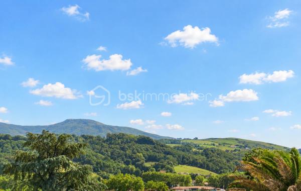 MAISON COUP DE CŒUR | VUE MONTAGNES | CALME | 15 MIN DE BAYONNE

Un emplacement privilégié, une vue dégagée, de beaux volumes et un potentiel remarquable…

Rare sur le secteur, cette charmante maison en position dominante vous séduira par son environnement paisible, 
sa vue ouverte sur les montagnes et sa proximité immédiate avec toutes les commodités.

Ici, tout se fait à pied : commerces, écoles, centre médical, activités sportives et services du quotidien. 
Et pour rejoindre Bayonne, comptez seulement 15 minutes.

 **UN CADRE DE VIE QUI FAIT LA DIFFÉRENCE**

Édifiée sur trois niveaux, la maison offre une organisation agréable et de nombreux espaces à exploiter.

Au niveau principal, vous découvrirez une belle pièce de vie baignée de lumière, prolongée par un balcon filant exposé plein Sud.

La cuisine ouverte s’intègre harmonieusement à l’espace de vie, tandis que le salon, agrémenté d’un insert, 
bénéficie d’un accès direct à une grande terrasse couverte exposée Sud-Est : un véritable prolongement de 
la maison pour profiter des beaux jours et des repas en extérieur.

Un bureau, une salle de bains et un WC indépendant complètent ce niveau.

 À L’ÉTAGE : 3 CHAMBRES ET DE BEAUX ESPACES

L’espace nuit se compose de 3 chambres, avec notamment :

* une chambre bénéficiant d’un petit balcon et d’un grenier ;
* une autre chambre avec dressing ;
* une troisième chambre idéale pour accueillir famille, enfants ou invités ;
* salle de bain avec WC et grenier.

90 M² AU REZ-DE-CHAUSSÉE : UN VÉRITABLE POTENTIEL

Le rez-de-chaussée constitue l’un des atouts majeurs de cette propriété.

Avec environ 90 m², il accueille actuellement un grand garage, un cellier, une buanderie et un WC.

Un volume particulièrement intéressant pour ceux qui souhaitent imaginer de nouveaux espaces selon 
leurs besoins et leurs projets : atelier, stockage, espace professionnel, salle de loisirs ou évolution de l'habitation, 
sous réserve des autorisations nécessaires.

L’accès au garage se fait directement depuis la maison par un escalier intérieur.

 **UN EXTÉRIEUR PRIVILÉGIÉ**

Côté jardin, vous profiterez d’un environnement agréable et préservé avec jardin et terrasse, ainsi que 
la possibilité de stationner jusqu’à 5 véhicules sur la propriété.

Un véritable confort au quotidien, particulièrement recherché sur le secteur.

**LES ÉQUIPEMENTS**

La maison dispose notamment de :

• Assainissement collectif – tout-à-l’égout
• Chauffage électrique par convecteurs
• Insert
• Fibre optique
• Panneaux solaires destinés à la revente, générant un **revenu annuel**

**POURQUOI ELLE VA VOUS PLAIRE**

✓ Une situation géographique privilégiée
✓ Le calme tout en étant à pied du centre et des commodités
✓ Une magnifique vue dégagée sur les montagnes
✓ Une exposition Sud et Sud-Est
✓ Environ 90 m² de garage et de potentiel au rez-de-chaussée
✓ 3 chambres + bureau
✓ Jardin et terrasse
✓ Stationnement pour 5 véhicules
✓ Panneaux photovoltaïques avec revenus annuels
✓ Bayonne à seulement 15 minutes

Une maison avec autant d'atouts et un tel emplacement est une opportunité rare sur le secteur.

Si vous recherchez un environnement calme, une belle qualité de vie, de la vue, de l’espace et la proximité 
de toutes les commodités, cette propriété mérite véritablement votre attention.

Je suis disponible 7 jours sur 7 et m’adapte à votre planning pour vous faire découvrir ce bien.

Contactez moi pour organiser votre visite.