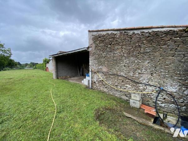 Bâtiment en pierre + préau et terrain en partie constructible