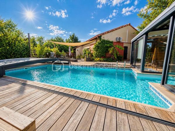 En exclusivité, idéalement située en plein centre de Labastidette, cette villa d’architecte bénéficie d’un emplacement pratique, à proximité des commerces, des services et des commodités du quotidien. Elle permet de profiter d’un cadre de vie résidentiel tout en restant facilement accessible depuis Muret et l’agglomération toulousaine.

Au cœur d’un environnement verdoyant, sur une parcelle paysagée d’environ 1 200 m², la propriété qui développe 220m2, séduit par son architecture singulière, ses volumes généreux, ses matériaux à la fois esthétiques et écologiques mais aussi par son efficience énergétique. Elle propose aujourd’hui 3 chambres, dont une suite parentale, ainsi que de nombreux espaces de vie conçus pour conjuguer confort, convivialité et ouverture sur les extérieurs. La pièce de réception s’organise autour d’un vaste séjour agrémenté d’une cuisine ouverte équipée et d’un espace bureau pouvant être isolé. Les ouvertures prolongent naturellement les espaces intérieurs vers les terrasses et le jardin, créant une continuité agréable entre la maison et son environnement paysager. L’étage s’ouvre sur un joli salon cosy et un couloir desservant une vaste chambre disposant de son bureau et son coin salon/détente.  

La propriété dispose également d’une piscine couverte et chauffée, véritable espace de détente utilisable en toute saison, ainsi que d’un lodge indépendant d’environ 45 m². Ce dernier, particulièrement chaleureux et apaisant, est intégralement voué à la détente. Composé d’un coin salon, d’un espace douche, d’un sauna ainsi que d’un grand jacuzzi, il s’ouvre sur la piscine lui conférant ainsi une accessibilité même en hiver.

Les extérieurs, soigneusement végétalisés, bénéficient de plusieurs espaces de vie et de stationnement. Un carport complète l’ensemble.

La maison est équipée d’une installation de chauffage au sol, d’un puits et de solutions énergétiques performantes (matériaux techniques, géothermie, panneaux solaires…). Elle bénéficie d’un DPE classé B, témoignant d’un niveau de performance énergétique favorable.

Cette propriété s’adresse à une clientèle recherchant un bien de caractère, aux volumes généreux, bénéficiant d’équipements rares et d’un cadre de vie privilégié aux portes de l’agglomération toulousaine.