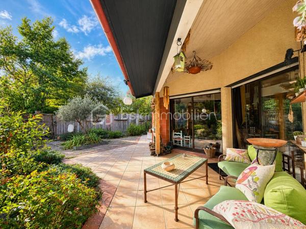 En exclusivité, idéalement située en plein centre de Labastidette, cette villa d’architecte bénéficie d’un emplacement pratique, à proximité des commerces, des services et des commodités du quotidien. Elle permet de profiter d’un cadre de vie résidentiel tout en restant facilement accessible depuis Muret et l’agglomération toulousaine.

Au cœur d’un environnement verdoyant, sur une parcelle paysagée d’environ 1 200 m², la propriété qui développe 220m2, séduit par son architecture singulière, ses volumes généreux, ses matériaux à la fois esthétiques et écologiques mais aussi par son efficience énergétique. Elle propose aujourd’hui 3 chambres, dont une suite parentale, ainsi que de nombreux espaces de vie conçus pour conjuguer confort, convivialité et ouverture sur les extérieurs. La pièce de réception s’organise autour d’un vaste séjour agrémenté d’une cuisine ouverte équipée et d’un espace bureau pouvant être isolé. Les ouvertures prolongent naturellement les espaces intérieurs vers les terrasses et le jardin, créant une continuité agréable entre la maison et son environnement paysager. L’étage s’ouvre sur un joli salon cosy et un couloir desservant une vaste chambre disposant de son bureau et son coin salon/détente.  

La propriété dispose également d’une piscine couverte et chauffée, véritable espace de détente utilisable en toute saison, ainsi que d’un lodge indépendant d’environ 45 m². Ce dernier, particulièrement chaleureux et apaisant, est intégralement voué à la détente. Composé d’un coin salon, d’un espace douche, d’un sauna ainsi que d’un grand jacuzzi, il s’ouvre sur la piscine lui conférant ainsi une accessibilité même en hiver.

Les extérieurs, soigneusement végétalisés, bénéficient de plusieurs espaces de vie et de stationnement. Un carport complète l’ensemble.

La maison est équipée d’une installation de chauffage au sol, d’un puits et de solutions énergétiques performantes (matériaux techniques, géothermie, panneaux solaires…). Elle bénéficie d’un DPE classé B, témoignant d’un niveau de performance énergétique favorable.

Cette propriété s’adresse à une clientèle recherchant un bien de caractère, aux volumes généreux, bénéficiant d’équipements rares et d’un cadre de vie privilégié aux portes de l’agglomération toulousaine.