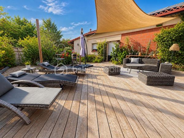 En exclusivité, idéalement située en plein centre de Labastidette, cette villa d’architecte bénéficie d’un emplacement pratique, à proximité des commerces, des services et des commodités du quotidien. Elle permet de profiter d’un cadre de vie résidentiel tout en restant facilement accessible depuis Muret et l’agglomération toulousaine.

Au cœur d’un environnement verdoyant, sur une parcelle paysagée d’environ 1 200 m², la propriété qui développe 220m2, séduit par son architecture singulière, ses volumes généreux, ses matériaux à la fois esthétiques et écologiques mais aussi par son efficience énergétique. Elle propose aujourd’hui 3 chambres, dont une suite parentale, ainsi que de nombreux espaces de vie conçus pour conjuguer confort, convivialité et ouverture sur les extérieurs. La pièce de réception s’organise autour d’un vaste séjour agrémenté d’une cuisine ouverte équipée et d’un espace bureau pouvant être isolé. Les ouvertures prolongent naturellement les espaces intérieurs vers les terrasses et le jardin, créant une continuité agréable entre la maison et son environnement paysager. L’étage s’ouvre sur un joli salon cosy et un couloir desservant une vaste chambre disposant de son bureau et son coin salon/détente.  

La propriété dispose également d’une piscine couverte et chauffée, véritable espace de détente utilisable en toute saison, ainsi que d’un lodge indépendant d’environ 45 m². Ce dernier, particulièrement chaleureux et apaisant, est intégralement voué à la détente. Composé d’un coin salon, d’un espace douche, d’un sauna ainsi que d’un grand jacuzzi, il s’ouvre sur la piscine lui conférant ainsi une accessibilité même en hiver.

Les extérieurs, soigneusement végétalisés, bénéficient de plusieurs espaces de vie et de stationnement. Un carport complète l’ensemble.

La maison est équipée d’une installation de chauffage au sol, d’un puits et de solutions énergétiques performantes (matériaux techniques, géothermie, panneaux solaires…). Elle bénéficie d’un DPE classé B, témoignant d’un niveau de performance énergétique favorable.

Cette propriété s’adresse à une clientèle recherchant un bien de caractère, aux volumes généreux, bénéficiant d’équipements rares et d’un cadre de vie privilégié aux portes de l’agglomération toulousaine.