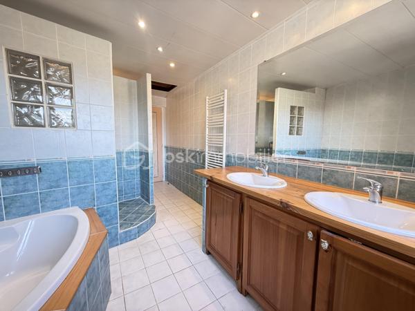 À 13 km de Voiron et 35 km de Grenoble, cette maison de village implantée en plein coeur d’Izeaux offre 142,82 m² habitables sur deux niveaux. Idéale pour une famille souhaitant s’installer dans un village animé, avec commerces et écoles à pied, à proximité des axes de transport vers Voiron et Grenoble.

Rez-de-chaussée :
Dès l’entrée, la maison révèle ses volumes : un salon de 24 m², belle pièce de vie à s’approprier, s’ouvre sur une cuisine spacieuse de 23 m² avec accès direct à la cour. Un cellier de 6,45 m² complète l’espace. La salle d’eau, entièrement neuve, avec douche à l’italienne et WC, a été conçue et aménagée pour l’accessibilité PMR.

Étage :
Quatre chambres dont une de 15 m² avec accès à un balcon, une de 12 m²,  de 11 m² et une de 10 m². Une grande salle de bain de 10 m² avec double vasque, douche et WC dessert l’ensemble.
Combles :
Environ 25 m² aménageables — une opportunité supplémentaire pour créer un espace bureau, une chambre d’amis ou une salle de jeux.

Extérieur :
À l’arrière, une cour  prolongent agréablement la maison pour profiter des beaux jours.
Côté stationnement, la maison dispose d'une place privative devant l'entrée. Un parking extérieur commun, à moins de 100 mètres, permet de garer facilement plusieurs véhicules.

Cadre de vie :
Le village d’Izeaux propose un cadre de vie paisible avec ses commerces de proximité, son marché hebdomadaire et ses écoles sur la commune. Les amateurs de nature profiteront des nombreux sentiers de randonnée et du jardin public situé à deux pas.

Travaux réalisés et équipements  :
Toiture refaite en 2023
Fenêtres PVC double vitrage
Chauffage : poêle à granulés (2017) + appoint électrique
Tout-à-l’égout

Travaux à prévoir
Rafraîchissement intérieur : remise en peinture de l'ensemble des pièces, rénovation des sols de la cuisine et du salon.
Travaux préconisés par l’audit énergétique :
Renforcement de l’isolation des murs (construction en pisé avec doublage insuffisant), installation d’une VMC, remplacement du chauffe-eau et installation d'une pompe à chaleur 
Estimation des coûts annuels d’énergie : entre 4 400 € et 6 000 € / an (estimation établie sur la base des prix de l’énergie 2021-2023).