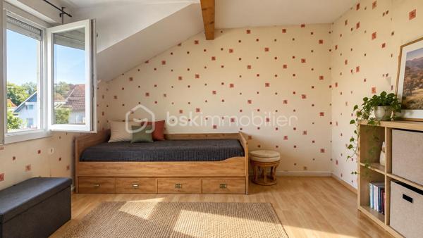 À Valleiry, dans un environnement résidentiel, profitez d’un cadre de vie familial, calme et pratique, à proximité de Genève.

UNE MAISON PENSÉE POUR LA VIE DE FAMILLE
Construite en 2004, cette maison de 7 pièces offre de beaux volumes et une organisation idéale pour une vie de famille confortable.
Répartie sur trois niveaux, elle propose 4 chambres, 2 salles de bains, 3 WC, un garage attenant, deux places de stationnement et un jardin clos.
Implantée sur une parcelle d’environ 274 m², au sein d’un lotissement résidentiel calme, la maison est mitoyenne par un seul côté, au niveau du garage et de la chambre située au-dessus, tout en conservant une réelle indépendance dans ses espaces de vie.
Elle bénéficie d’une situation préservée, sans accès direct sur la route et à l’écart des nuisances sonores.

LE COUP DE CŒUR : UNE VÉRANDA CHAUFFÉE DE 20 M²
Baignée de lumière et largement ouverte sur le jardin, la véranda prolonge agréablement les espaces de vie et crée une atmosphère chaleureuse en toute saison.
Salle à manger conviviale, salon détente, salle de jeux, coin lecture ou espace pour recevoir : chacun pourra imaginer cette pièce selon son mode de vie.

REZ-DE-JARDIN : DES ESPACES FLUIDES ET LUMINEUX
Le rez-de-jardin offre une distribution agréable et fonctionnelle.
L’entrée ouvre sur une belle pièce de vie lumineuse d’environ 36 m², composée d’un séjour et d’une cuisine ouverte, avec un premier WC indépendant.
La pièce de vie se prolonge naturellement vers la véranda ouverte sur le jardin.
Le garage attenant, accessible également depuis la véranda, apporte un espace pratique supplémentaire au quotidien.

PREMIER ÉTAGE : MEZZANINE, 2 CHAMBRES ET SUITE PARENTALE
Une spacieuse mezzanine d’environ 16 m² offre un espace polyvalent, idéal pour aménager un bureau, un coin lecture, une salle de jeux ou un espace TV.
Ce niveau comprend également deux chambres, dont une chambre parentale avec salle de bains privative, ainsi qu’un deuxième WC.

DEUXIÈME ÉTAGE : 2 CHAMBRES SUPPLÉMENTAIRES
Le dernier niveau accueille deux autres chambres, des rangements, une seconde salle de bains et un troisième WC, offrant à chacun son propre espace.

CONFORT ET CHAUFFAGE
Le chauffage principal est assuré par un poêle à granulés, relayé si besoin par des convecteurs électriques.

SECTEUR ET COMMODITÉS
La situation est idéale pour concilier vie de famille, quotidien pratique et déplacements vers le bassin genevois.
La douane de Chancy permet de rejoindre rapidement Genève et constitue un véritable atout pour les actifs frontaliers souhaitant profiter d’un cadre résidentiel calme tout en restant proches de leur lieu de travail.
Pour les familles, le groupe scolaire Les Primevères, de la maternelle au CM2, est accessible à pied, tandis que le Collège du Vuache à Vulbens se situe à environ 10 minutes, avec des transports scolaires au départ de Valleiry.
Au quotidien, tout est à portée de main : supermarché, boulangeries, pharmacie, professionnels de santé, banques, bureau de poste, restaurants et gare SNCF.

À DÉCOUVRIR
Un bien familial complet, fonctionnel et idéalement situé, qui conjugue espace, calme, praticité et proximité de Genève.