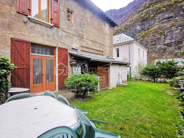 Située dans un environnement paisible sur la commune de Livet-Gavet, cette maison mitoyenne RENOVEE et PLEINE DE CHARME d’environ 109 m² (117 m² au sol) constitue une OPPORTUNITE IDEALE POUR UNE FAMILLE à la recherche de confort et de tranquillité.

Son emplacement est un véritable atout : à deux pas de l’école maternelle, à proximité immédiate de la voie verte et à seulement 19 minutes du téléporté d’Allemond, permettant un accès rapide au domaine skiable de Alpe d’Huez ainsi qu’aux stations prisées de l’Oisans. Un cadre de vie privilégié entre nature, montagne et commodités.

En Rez-de-chaussée un SPACIEUX salon/salle à manger lumineux et chaleureux, offrant un accès au JARDIN FLEURI et à la VUE DEGAGEE; une agréable cuisine attenante donne accès à la TERRASSE DINATOIRE; un WC indépendant.

L' étage propose DEUX CHAMBRES aux belles dimensions; un BUREAU; ainsi qu’une salle d’eau. Les combles aménagés constituent un véritable atout supplémentaire avec une VASTE CHAMBRE DOTEE D'UN DRESSING, pouvant également servir de salle de jeux ou d'espace détente; un ESPACE SUPPLEMENTAIRE à ce niveau vous offre la possibilité de rangements ou d'une pièce en plus à aménager selon vos goûts.

L’extérieur d'environ 100m² présente une TERRASSE DINATOIRE, un joli JARDIN FLEURI à la VUE DEGAGEE, parfait pour des moments de convivialité. De plus, un CABANON,  un GRENIER ainsi que d’une CAVE VOUTEE faisant office de chaufferie, offre un potentiel de stockage appréciable.

Très bien entretenue, la maison bénéficie de prestations techniques de qualité avec une POMPE A CHALEUR récente installée en 2023, des menuiseries en DOUBLE ET TRIPLE VITRAGE, le raccordement au tout-à-l’égout ainsi que la FIBRE; Classée DPE C, elle assure une CONSOMMATION ENERGETIQUE MAITRISEE, idéale pour le confort au quotidien et la maîtrise des dépenses.

Ce bien séduit par son équilibre entre charme, volumes généreux et emplacement stratégique, en faisant une opportunité rare sur le secteur, particulièrement adaptée à une famille grâce à la proximité immédiate des écoles.

Des places de stationnement sont disponibles à proximité et un GARAGE peut être proposé en complément.