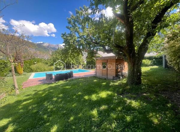 Amoureux des lieux atypiques, cette maison est faite pour vous.
Découvrez cette maison d’architecte de 191 m² habitables, offrant 7 pièces aux volumes généreux et aux espaces de vie chaleureux et lumineux, 
le tout implanté sur un terrain de 1 523 m². 
Elle se situe dans un secteur recherché, à proximité des commerces et des stations de ski de la Maurienne.
Exposée plein sud, cette propriété rénovée en 2020 bénéficie d’une belle luminosité naturelle et d’une architecture intérieure originale, 
idéale pour les amateurs de biens authentiques et de caractère.
Édifiée sur deux niveaux, elle séduit dès l’entrée par son vaste hall baigné de lumière, grâce à ses grandes baies vitrées.

Au rez-de-chaussée, vous découvrirez une cuisine entièrement équipée ouverte sur le séjour, avec accès direct à la terrasse extérieure. 
Une magnifique cheminée traversante double foyer vient harmonieusement séparer le séjour du salon, apportant charme et convivialité à l’ensemble.
Le séjour, sublimé par un parquet en bois massif, renforce le caractère chaleureux et raffiné de la maison.
Ce niveau comprend également deux chambres, dont une suite parentale avec salle d’eau privative et accès à une véranda équipée d’une cuisine, 
permettant si besoin de créer un espace indépendant.
Un coin buanderie ainsi qu’un WC séparé viennent compléter ce niveau.
Les belles hauteurs sous plafond et les nombreuses ouvertures accentuent la sensation d’espace et l’atmosphère conviviale de cette propriété unique.

Un élégant escalier mène à l’étage, où vous découvrirez trois chambres confortables, de 13 à 25 m², chacune sublimée par de magnifiques poutres apparentes, 
apportant charme et authenticité.
Vous y trouverez également une salle de bains familiale avec toilettes, ainsi qu’une superbe mezzanine de 25 m², 
habillée d’un parquet massif et aménagée en second salon, surplombant la pièce de vie du rez-de-chaussée et offrant une remarquable sensation d’espace et de volume.

Les extérieurs, soigneusement aménagés, offrent un véritable espace de détente et de convivialité. 
Vous profiterez d’une grande terrasse, d’une piscine au sel chauffée par pompe à chaleur, parfaitement intégrée avec sa terrasse en composite, 
d’un jacuzzi, ainsi que d’un chalet de jardin. 
Le terrain, entièrement clos et paysager, apporte calme et intimité à l’ensemble de la propriété.

Côté dépendances, ce bien dispose également d’un double garage, de deux caves ainsi que d’un carport pouvant accueillir jusqu’à trois véhicules.
Enfin, la maison est équipée de panneaux photovoltaïques, permettant de couvrir une grande partie de la consommation électrique du logement.