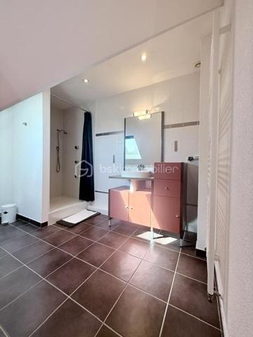 Nichée au cœur d’un quartier résidentiel très recherché, découvrez cette magnifique propriété individuelle de caractère (construction 2002). Accessible par une voie privée garantissant une discrétion absolue, elle offre un cadre de vie rare et privilégié, où confort moderne rhyme avec sérénité. Une véritable maison "prête à vivre", sans aucun travaux à prévoir.

 Des volumes lumineux et harmonieux

Au rez-de-chaussée :
Espace de vie : Un vaste salon-séjour baigné de lumière, ouvert sur une cuisine conviviale et entièrement équipée avec son cellier attenant. Le tout donne un accès direct à la terrasse pour des moments partagés.

Espace de travail : Un vrai bureau, idéal pour le télétravail ou une pièce de lecture.

Accueil : Une entrée fonctionnelle avec placards intégrés et WC invités.

Le plus confort : Chauffage au sol intégral pour une douce chaleur homogène.

À l’étage :

Suite parentale : Un espace élégant avec placards intégrés et sa salle d'eau privative.

Chambres : Deux belles chambres supplémentaires dont une avec placards mural, parfaites pour des enfants ou des invités.

Salle de bain : Une oasis familiale raffinée avec baignoire, douche et double vasque.

Le charme de l'architecture : Les volumes sous toiture apportent un cachet fou et une atmosphère intimiste.

 Un extérieur paysager d'exception
Le jardin de 10,5 ares, soigneusement arboré et entretenu, a été pensé comme une extension de la maison :

Terrasse de 28 m² équipée d'un store motorisé, idéale pour vos repas d'été.

Dépendance : Une coquette maisonnette de jardin de près de 15 m² (atelier, stockage).

Facilité du quotidien : Système d'arrosage automatique pour un vert parfait sans effort.

 Annexes et stationnement haut de gamme
Garage double : Isolé, carrelé, avec porte motorisée (accès direct et propre).

Carport : Capacité de stationnement pour 3 véhicules à l'abri.

Cour : Plusieurs places de stationnement extérieures privatives.

 Prestations techniques & Qualité
Adoucisseur d’eau • Volets roulants électriques • Chauffage au sol • Entretien irréprochable • Matériaux de qualité.

Notre avis : Un bien rare sur le secteur. Si vous recherchez de l'espace, de la tranquillité et des prestations soignées, cette maison d'architecte n'attend plus que vos valises.

Visites privées sur rendez-vous uniquement. Contactez-moi dès aujourd'hui pour planifier votre découverte de ce bien d'exception.