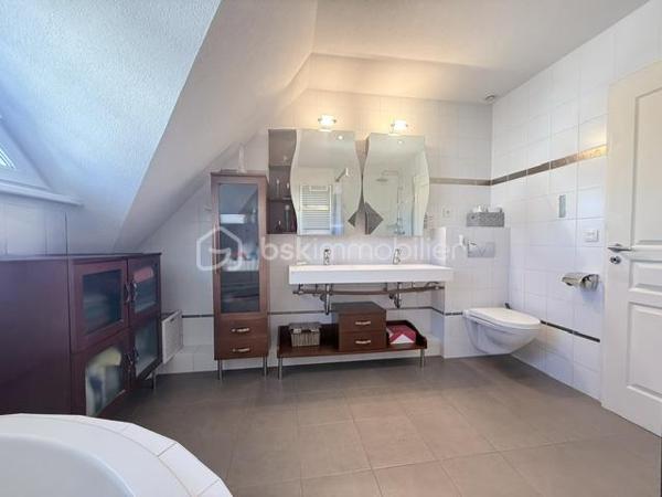 Nichée au cœur d’un quartier résidentiel très recherché, découvrez cette magnifique propriété individuelle de caractère (construction 2002). Accessible par une voie privée garantissant une discrétion absolue, elle offre un cadre de vie rare et privilégié, où confort moderne rhyme avec sérénité. Une véritable maison "prête à vivre", sans aucun travaux à prévoir.

 Des volumes lumineux et harmonieux

Au rez-de-chaussée :
Espace de vie : Un vaste salon-séjour baigné de lumière, ouvert sur une cuisine conviviale et entièrement équipée avec son cellier attenant. Le tout donne un accès direct à la terrasse pour des moments partagés.

Espace de travail : Un vrai bureau, idéal pour le télétravail ou une pièce de lecture.

Accueil : Une entrée fonctionnelle avec placards intégrés et WC invités.

Le plus confort : Chauffage au sol intégral pour une douce chaleur homogène.

À l’étage :

Suite parentale : Un espace élégant avec placards intégrés et sa salle d'eau privative.

Chambres : Deux belles chambres supplémentaires dont une avec placards mural, parfaites pour des enfants ou des invités.

Salle de bain : Une oasis familiale raffinée avec baignoire, douche et double vasque.

Le charme de l'architecture : Les volumes sous toiture apportent un cachet fou et une atmosphère intimiste.

 Un extérieur paysager d'exception
Le jardin de 10,5 ares, soigneusement arboré et entretenu, a été pensé comme une extension de la maison :

Terrasse de 28 m² équipée d'un store motorisé, idéale pour vos repas d'été.

Dépendance : Une coquette maisonnette de jardin de près de 15 m² (atelier, stockage).

Facilité du quotidien : Système d'arrosage automatique pour un vert parfait sans effort.

 Annexes et stationnement haut de gamme
Garage double : Isolé, carrelé, avec porte motorisée (accès direct et propre).

Carport : Capacité de stationnement pour 3 véhicules à l'abri.

Cour : Plusieurs places de stationnement extérieures privatives.

 Prestations techniques & Qualité
Adoucisseur d’eau • Volets roulants électriques • Chauffage au sol • Entretien irréprochable • Matériaux de qualité.

Notre avis : Un bien rare sur le secteur. Si vous recherchez de l'espace, de la tranquillité et des prestations soignées, cette maison d'architecte n'attend plus que vos valises.

Visites privées sur rendez-vous uniquement. Contactez-moi dès aujourd'hui pour planifier votre découverte de ce bien d'exception.