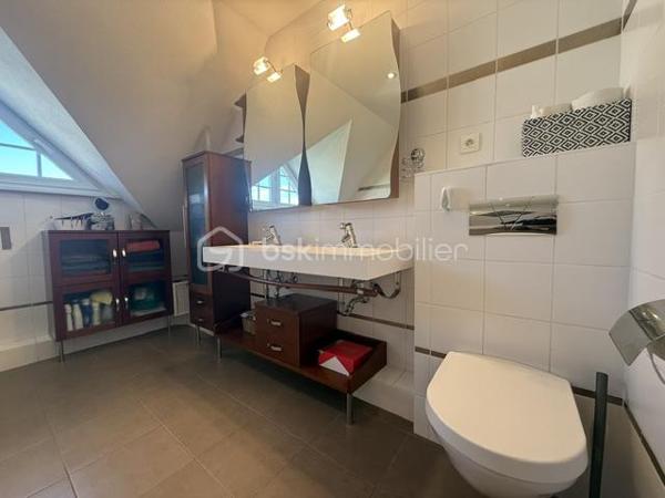 Nichée au cœur d’un quartier résidentiel très recherché, découvrez cette magnifique propriété individuelle de caractère (construction 2002). Accessible par une voie privée garantissant une discrétion absolue, elle offre un cadre de vie rare et privilégié, où confort moderne rhyme avec sérénité. Une véritable maison "prête à vivre", sans aucun travaux à prévoir.

 Des volumes lumineux et harmonieux

Au rez-de-chaussée :
Espace de vie : Un vaste salon-séjour baigné de lumière, ouvert sur une cuisine conviviale et entièrement équipée avec son cellier attenant. Le tout donne un accès direct à la terrasse pour des moments partagés.

Espace de travail : Un vrai bureau, idéal pour le télétravail ou une pièce de lecture.

Accueil : Une entrée fonctionnelle avec placards intégrés et WC invités.

Le plus confort : Chauffage au sol intégral pour une douce chaleur homogène.

À l’étage :

Suite parentale : Un espace élégant avec placards intégrés et sa salle d'eau privative.

Chambres : Deux belles chambres supplémentaires dont une avec placards mural, parfaites pour des enfants ou des invités.

Salle de bain : Une oasis familiale raffinée avec baignoire, douche et double vasque.

Le charme de l'architecture : Les volumes sous toiture apportent un cachet fou et une atmosphère intimiste.

 Un extérieur paysager d'exception
Le jardin de 10,5 ares, soigneusement arboré et entretenu, a été pensé comme une extension de la maison :

Terrasse de 28 m² équipée d'un store motorisé, idéale pour vos repas d'été.

Dépendance : Une coquette maisonnette de jardin de près de 15 m² (atelier, stockage).

Facilité du quotidien : Système d'arrosage automatique pour un vert parfait sans effort.

 Annexes et stationnement haut de gamme
Garage double : Isolé, carrelé, avec porte motorisée (accès direct et propre).

Carport : Capacité de stationnement pour 3 véhicules à l'abri.

Cour : Plusieurs places de stationnement extérieures privatives.

 Prestations techniques & Qualité
Adoucisseur d’eau • Volets roulants électriques • Chauffage au sol • Entretien irréprochable • Matériaux de qualité.

Notre avis : Un bien rare sur le secteur. Si vous recherchez de l'espace, de la tranquillité et des prestations soignées, cette maison d'architecte n'attend plus que vos valises.

Visites privées sur rendez-vous uniquement. Contactez-moi dès aujourd'hui pour planifier votre découverte de ce bien d'exception.