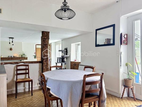 Si vous recherchez l'authenticité de la pierre, du caractère et de l'espace pour toute la famille, cette maison d'environ 98 m² (hors véranda) saura vous séduire. A quelques minutes de Bricquebec, cette maison de caractère avec ses poutres apparentes et ses volumes chaleureux est implantée sur une magnifique parcelle close et arborée de plus de 1 500 m².

​🛋️ Le rez-de-chaussée : De la lumière et du caractère. 🌞

L'accueil se fait par une agréable et lumineuse véranda qui sert d'entrée à la maison. Elle s'ouvre ensuite sur une belle pièce de vie de plus de 30 m² où le salon, réchauffé par une authentique cheminée avec insert, côtoie l'espace salle à manger. Une superbe poutre en bois brut vient rythmer cet espace sans le cloisonner.
La cuisine aménagée s'ouvre sur le séjour via un comptoir en bois très convivial, idéal pour déjeuner sur le pouce, et se prolonge par une arrière-cuisine (cellier) bien pratique.
Ce niveau propose également une suite avec sa chambre (bénéficiant d'une porte-fenêtre sur le jardin) et sa salle de bain privative avec baignoire et WC.

​🛌 L’étage : Le charme des boiseries et le coin nuit

L’escalier en bois dessert trois chambres mansardées au caractère authentique rehaussé par des poutres apparentes. L'une d'entre elles est idéale pour un espace bureau ou télétravail. Cet espace de nuit, fonctionnel, nécessite un petit rafraîchissement (peintures, papiers peints) pour révéler tout son potentiel et être mis à votre goût. Pour le confort de la famille au quotidien, ce niveau dispose d'une salle de douche et de deux WC.

​🌳 Les extérieurs et annexes : un vrai coup de cœur. 🧡

Le grand jardin accueille une terrasse d'environ 20 m² avec son barbecue fixe, prête pour les repas d'été.

✨ Le véritable atout caché ? Une superbe dépendance en pierre, déjà raccordée en eau et en électricité. Bien qu'elle nécessite une rénovation totale, elle offre un potentiel incroyable : futur gîte, atelier d'artiste ou studio d'invités.

Un cabanon de jardin fonctionnel (avec électricité et chauffage d'appoint) complètent le tout.