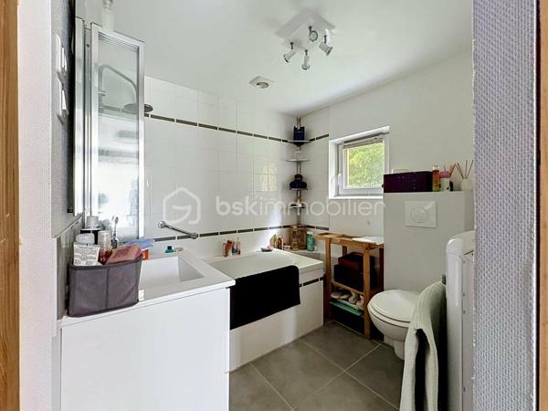 Si vous recherchez l'authenticité de la pierre, du caractère et de l'espace pour toute la famille, cette maison d'environ 98 m² (hors véranda) saura vous séduire. A quelques minutes de Bricquebec, cette maison de caractère avec ses poutres apparentes et ses volumes chaleureux est implantée sur une magnifique parcelle close et arborée de plus de 1 500 m².

​🛋️ Le rez-de-chaussée : De la lumière et du caractère. 🌞

L'accueil se fait par une agréable et lumineuse véranda qui sert d'entrée à la maison. Elle s'ouvre ensuite sur une belle pièce de vie de plus de 30 m² où le salon, réchauffé par une authentique cheminée avec insert, côtoie l'espace salle à manger. Une superbe poutre en bois brut vient rythmer cet espace sans le cloisonner.
La cuisine aménagée s'ouvre sur le séjour via un comptoir en bois très convivial, idéal pour déjeuner sur le pouce, et se prolonge par une arrière-cuisine (cellier) bien pratique.
Ce niveau propose également une suite avec sa chambre (bénéficiant d'une porte-fenêtre sur le jardin) et sa salle de bain privative avec baignoire et WC.

​🛌 L’étage : Le charme des boiseries et le coin nuit

L’escalier en bois dessert trois chambres mansardées au caractère authentique rehaussé par des poutres apparentes. L'une d'entre elles est idéale pour un espace bureau ou télétravail. Cet espace de nuit, fonctionnel, nécessite un petit rafraîchissement (peintures, papiers peints) pour révéler tout son potentiel et être mis à votre goût. Pour le confort de la famille au quotidien, ce niveau dispose d'une salle de douche et de deux WC.

​🌳 Les extérieurs et annexes : un vrai coup de cœur. 🧡

Le grand jardin accueille une terrasse d'environ 20 m² avec son barbecue fixe, prête pour les repas d'été.

✨ Le véritable atout caché ? Une superbe dépendance en pierre, déjà raccordée en eau et en électricité. Bien qu'elle nécessite une rénovation totale, elle offre un potentiel incroyable : futur gîte, atelier d'artiste ou studio d'invités.

Un cabanon de jardin fonctionnel (avec électricité et chauffage d'appoint) complètent le tout.