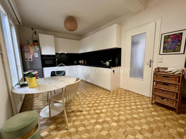 À proximité immédiate du centre-ville, des gares, des axes autoroutiers et de la tangentielle, cette authentique maison des années 1930 séduira les amoureux de cachet, d’espaces chaleureux et de projets de vie polyvalents.

Dès l’entrée, un couloir distribue : • une première chambre, • un toilette indépendant avec lave-mains, • une seconde chambre.
La visite se poursuit vers une cuisine récente, aménagée et équipée, ouverte sur une superbe extension baignée de lumière. Cette pièce de vie au charme incomparable offre une cheminée, une belle hauteur sous plafond et de magnifiques poutres apparentes. Grâce à ses larges ouvertures sur le jardin, l’intérieur et l’extérieur se répondent harmonieusement tout au long de l’année.

À l’étage, un palier aménagé en coin bibliothèque dessert : • une chambre, • une salle d’eau avec toilette, lavabo et bidet.
La maison bénéficie également d’un sous-sol complet comprenant plusieurs caves, une chaufferie ainsi qu’une pièce de 25 m² pouvant être aménagée en espace habitable, bureau indépendant, salle de loisirs ou studio selon vos besoins.

À l’extérieur, le jardin intimiste et arboré accueille : • un atelier indépendant d’environ 40 m², • deux garages de plus de 16 m² chacun, situés au fond du terrain, • une agréable terrasse ombragée par un magnifique tilleul.
Ces dépendances offrent un véritable potentiel pour une activité professionnelle ou un investissement locatif : atelier d’artiste, cabinet de profession libérale, espace de coworking, activité artisanale, stockage, studio indépendant ou bureaux.
Cette propriété conviendra parfaitement : • à un artisan souhaitant disposer d’un atelier à domicile, • à un artiste ou créatif recherchant un espace de travail indépendant, • à un professionnel libéral (architecte, thérapeute, coach, consultant, profession paramédicale…), • ou encore à un investisseur désirant exploiter les dépendances pour du locatif ou une activité complémentaire.

Une maison pleine d’âme et de possibilités, idéale pour conjuguer vie personnelle, activité professionnelle et projet patrimonial.

Taxe foncière: 2268€
Energie: 238€/mois