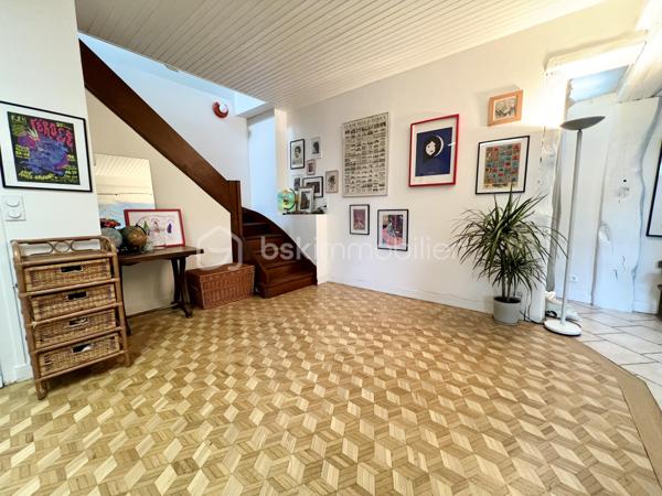 À proximité immédiate du centre-ville, des gares, des axes autoroutiers et de la tangentielle, cette authentique maison des années 1930 séduira les amoureux de cachet, d’espaces chaleureux et de projets de vie polyvalents.

Dès l’entrée, un couloir distribue : • une première chambre, • un toilette indépendant avec lave-mains, • une seconde chambre.
La visite se poursuit vers une cuisine récente, aménagée et équipée, ouverte sur une superbe extension baignée de lumière. Cette pièce de vie au charme incomparable offre une cheminée, une belle hauteur sous plafond et de magnifiques poutres apparentes. Grâce à ses larges ouvertures sur le jardin, l’intérieur et l’extérieur se répondent harmonieusement tout au long de l’année.

À l’étage, un palier aménagé en coin bibliothèque dessert : • une chambre, • une salle d’eau avec toilette, lavabo et bidet.
La maison bénéficie également d’un sous-sol complet comprenant plusieurs caves, une chaufferie ainsi qu’une pièce de 25 m² pouvant être aménagée en espace habitable, bureau indépendant, salle de loisirs ou studio selon vos besoins.

À l’extérieur, le jardin intimiste et arboré accueille : • un atelier indépendant d’environ 40 m², • deux garages de plus de 16 m² chacun, situés au fond du terrain, • une agréable terrasse ombragée par un magnifique tilleul.
Ces dépendances offrent un véritable potentiel pour une activité professionnelle ou un investissement locatif : atelier d’artiste, cabinet de profession libérale, espace de coworking, activité artisanale, stockage, studio indépendant ou bureaux.
Cette propriété conviendra parfaitement : • à un artisan souhaitant disposer d’un atelier à domicile, • à un artiste ou créatif recherchant un espace de travail indépendant, • à un professionnel libéral (architecte, thérapeute, coach, consultant, profession paramédicale…), • ou encore à un investisseur désirant exploiter les dépendances pour du locatif ou une activité complémentaire.

Une maison pleine d’âme et de possibilités, idéale pour conjuguer vie personnelle, activité professionnelle et projet patrimonial.

Taxe foncière: 2268€
Energie: 238€/mois