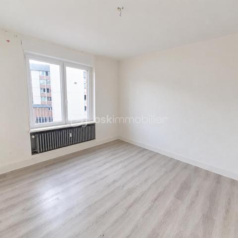 Situé au 3ᵉ étage du bâtiment annulaire, rue Auguste-Wicky à Mulhouse, cet appartement de 92 m² bénéficie d'un emplacement privilégié, à proximité immédiate de la gare et à deux pas du centre historique. Ses beaux volumes et sa configuration offrent de nombreuses possibilités d'aménagement.

Une adresse emblématique de Mulhouse
Construit dans les années 1950 par l'architecte Pierre-Jean Guth, le bâtiment annulaire est un édifice singulier de l'architecture mulhousienne d'après-guerre. Sa forme circulaire remarquable et son histoire lui ont valu une inscription au titre des monuments historiques en 2006. Une adresse de caractère, au cœur d'un ensemble architectural qui fait partie du patrimoine de la ville.

Un appartement à aménager selon votre projet
L'appartement se compose d'une large entrée, de quatre belles pièces de 11, 12, 16 et 17 m², offrant différentes possibilités d'aménagement selon les besoins de chacun. Une cuisine indépendante, une salle de bains, un WC séparé et un petit balcon complètent le bien.
Des travaux de rénovation sont à prévoir, laissant la possibilité de repenser les espaces et les prestations selon vos envies. Un devis a déjà été réalisé afin de permettre aux acquéreurs d'anticiper le budget nécessaire à leur projet.
À l'arrière de l'immeuble, la cour intérieure verdoyante entretenue par la Ville de Mulhouse apportent une touche de nature en milieu urbain. Le bien dispose également d'une cave. Des possibilités de stationnement existent à l'arrière de l'immeuble, sous réserve de disponibilité.

Que ce soit pour créer un lieu de vie personnalisé ou pour réaliser un investissement locatif, cet appartement présente un potentiel intéressant. Le règlement de copropriété autorise la location de courte durée, un atout supplémentaire pour les acquéreurs souhaitant étudier cette possibilité, sous réserve du respect de la réglementation applicable.

Informations complémentaires
- Surface : 92 m²
- Étage : 3ᵉ
- Chauffage collectif au gaz
- DPE : D — GES : D
- Taxe foncière : 1 200 € par an
- Charges annuelles comprennant charges générales de l'immeuble, eau chaude, eau froide et chauffage (5830€ de charges locatives sur 6283€ en 2025)