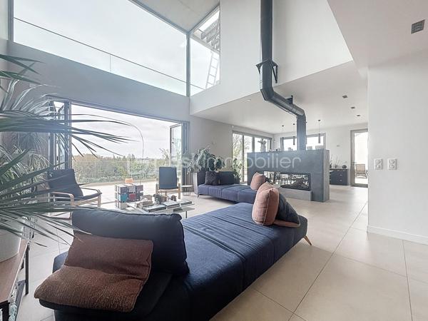 L’art de vivre contemporain aux portes de Paris! 
Située dans un environnement résidentiel privilégié en bord de Seine, cette exceptionnelle villa d’architecte neuve de 357 m² habitables offre un panorama spectaculaire sur la Seine, La Défense et la Tour Eiffel.
Édifiée sur un terrain paysager de 1 744 m², cette propriété séduit par ses volumes généreux, sa luminosité omniprésente, ses prestations haut de gamme et son architecture contemporaine ouverte sur l’extérieur. Les vastes terrasses bois avec claustras et brise-soleil, la piscine de 46 m²chauffée avec espace détente et une cuisine d’été et le séjour cathédrale avec cheminée centrale 360° créent une atmosphère unique entre élégance, confort et art de vivre.

Une distribution pensée pour le confort et la réception. 
•	11 pièces principales 
•	8 chambres dont 3 avec accès terrasse et 1 avec accès PMR
•	Suite parentale avec dressing, salle de bains et terrasse 
•	7 salles d’eau dont 6 privatives 
•	Salle à manger et séjour cathédrale avec vue panoramique 
•	Cuisine américaine avec cellier fermé
•	Appartement indépendant avec 2 chambres et 1 séjour cuisine américaine
•	Garage fermé 3 véhicules + stationnements extérieurs 
À cela s’ajoutent plusieurs espaces annexes non comptabilisés dans la surface habitable : une buanderie, une cave à vins et deux locaux techniques dédiés à la piscine de 46 m² ainsi qu’aux équipements énergétiques de la propriété, pompes à chaleur et centrale double flux.

Rez-de-chaussée surélevé: 
Le niveau principal offre une cuisine américaine avec cellier ouverte sur un spectaculaire séjour cathédrale avec cheminée centrale 360°, baigné de lumière et prolongé par les terrasses et la piscine.
Une salle à manger élégante complète les espaces de réception.
Ce niveau accueille également :
- une chambre avec salle d’eau et WC accessibles PMR (rampe extérieure),
- une suite parentale avec terrasse, dressing, salle de bains avec baignoire et douche à l’italienne double ciel de pluie, ainsi que des WC séparés.

Étage: 
Un élégant escalier sculptural en bois massif, conçu comme une estrade bibliothèque contemporaine, mène à l’étage desservi par une passerelle architecturale.
L’espace nuit comprend :
- 4 chambres avec salle d’eau privative, dont 2 avec terrasse et vue panoramique,
- 2 WC séparés,
- Rangements et gaine à linge reliant directement la buanderie.

Rez-de-jardin : 
Le rez-de-jardin propose des espaces fonctionnels comprenant une entrée indépendante, un vestiaire, une buanderie, une cave à vins, des rangements et un local technique équipé de pompes à chaleur et d’une centrale double flux alimentée par panneaux solaires et photovoltaïques.
Un appartement indépendant complète ce niveau avec:
- séjour et cuisine ouverte
- 2 chambres
- 1 salle d’eau et WC séparés

Environnement & cadre de vie
Cadre résidentiel privilégié en bord de Seine, offrant un équilibre rare entre nature et proximité de Paris.
•	Berges de Seine et chemin de halage à 2 min à pied 
•	Parcours des Impressionnistes à proximité 
•	Île des Impressionnistes de Chatou à 10 min 
•	Jardins de Mademoiselle de La Vallière à 10 min à pied 
Vie de quartier & commodités
À seulement 12 km de Paris, accès rapide aux transports et principaux pôles d’affaires.
•	Gare Houilles / Carrières-sur-Seine (RER A, lignes J & L) à 10 min 
•	Paris Saint-Lazare en 24 min 
•	Accès rapide A86, A14 et La Défense 
•	Commerces et supermarchés à proximité immédiate 

Établissements scolaires
Écoles, collège et lycée accessibles rapidement.
Établissements bilingues et internationaux à proximité : Montessori bilingue, The British School of Paris, Lycée International de Saint-Germain-en-Laye et Ermitage International School.

Prestations & équipements haut de gamme
•	Construction RT 2012 – Prestations énergétiques premium DPE A
•	Plancher chauffant et rafraîchissant sur 3 niveaux 
•	Pompe à chaleur, climatisation et centrale double flux 
•	Panneaux solaires hybrides et photovoltaïques 
•	Menuiseries aluminium, double vitrage et volets motorisés 
•	Cheminée centrale 360° 
•	Piscine chauffée avec espace détente 
•	3 Terrasses bois et pierre avec brise-soleil et claustras 
•	Garage fermé 3 véhicules + stationnements extérieurs 
•	Matériaux nobles et finitions premium

Une propriété rare destinée aux amateurs de lieux uniques recherchant un équilibre parfait entre nature, architecture contemporaine et proximité immédiate de Paris.
Découvrez cette propriété d’exception lors d’une visite privée.