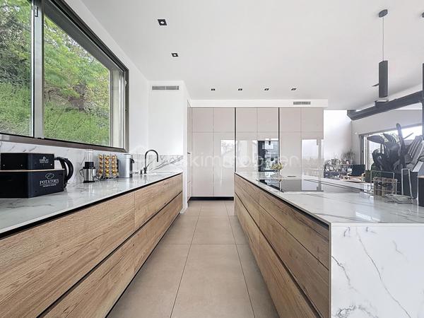 L’art de vivre contemporain aux portes de Paris! 
Située dans un environnement résidentiel privilégié en bord de Seine, cette exceptionnelle villa d’architecte neuve de 357 m² habitables offre un panorama spectaculaire sur la Seine, La Défense et la Tour Eiffel.
Édifiée sur un terrain paysager de 1 744 m², cette propriété séduit par ses volumes généreux, sa luminosité omniprésente, ses prestations haut de gamme et son architecture contemporaine ouverte sur l’extérieur. Les vastes terrasses bois avec claustras et brise-soleil, la piscine de 46 m²chauffée avec espace détente et une cuisine d’été et le séjour cathédrale avec cheminée centrale 360° créent une atmosphère unique entre élégance, confort et art de vivre.

Une distribution pensée pour le confort et la réception. 
•	11 pièces principales 
•	8 chambres dont 3 avec accès terrasse et 1 avec accès PMR
•	Suite parentale avec dressing, salle de bains et terrasse 
•	7 salles d’eau dont 6 privatives 
•	Salle à manger et séjour cathédrale avec vue panoramique 
•	Cuisine américaine avec cellier fermé
•	Appartement indépendant avec 2 chambres et 1 séjour cuisine américaine
•	Garage fermé 3 véhicules + stationnements extérieurs 
À cela s’ajoutent plusieurs espaces annexes non comptabilisés dans la surface habitable : une buanderie, une cave à vins et deux locaux techniques dédiés à la piscine de 46 m² ainsi qu’aux équipements énergétiques de la propriété, pompes à chaleur et centrale double flux.

Rez-de-chaussée surélevé: 
Le niveau principal offre une cuisine américaine avec cellier ouverte sur un spectaculaire séjour cathédrale avec cheminée centrale 360°, baigné de lumière et prolongé par les terrasses et la piscine.
Une salle à manger élégante complète les espaces de réception.
Ce niveau accueille également :
- une chambre avec salle d’eau et WC accessibles PMR (rampe extérieure),
- une suite parentale avec terrasse, dressing, salle de bains avec baignoire et douche à l’italienne double ciel de pluie, ainsi que des WC séparés.

Étage: 
Un élégant escalier sculptural en bois massif, conçu comme une estrade bibliothèque contemporaine, mène à l’étage desservi par une passerelle architecturale.
L’espace nuit comprend :
- 4 chambres avec salle d’eau privative, dont 2 avec terrasse et vue panoramique,
- 2 WC séparés,
- Rangements et gaine à linge reliant directement la buanderie.

Rez-de-jardin : 
Le rez-de-jardin propose des espaces fonctionnels comprenant une entrée indépendante, un vestiaire, une buanderie, une cave à vins, des rangements et un local technique équipé de pompes à chaleur et d’une centrale double flux alimentée par panneaux solaires et photovoltaïques.
Un appartement indépendant complète ce niveau avec:
- séjour et cuisine ouverte
- 2 chambres
- 1 salle d’eau et WC séparés

Environnement & cadre de vie
Cadre résidentiel privilégié en bord de Seine, offrant un équilibre rare entre nature et proximité de Paris.
•	Berges de Seine et chemin de halage à 2 min à pied 
•	Parcours des Impressionnistes à proximité 
•	Île des Impressionnistes de Chatou à 10 min 
•	Jardins de Mademoiselle de La Vallière à 10 min à pied 
Vie de quartier & commodités
À seulement 12 km de Paris, accès rapide aux transports et principaux pôles d’affaires.
•	Gare Houilles / Carrières-sur-Seine (RER A, lignes J & L) à 10 min 
•	Paris Saint-Lazare en 24 min 
•	Accès rapide A86, A14 et La Défense 
•	Commerces et supermarchés à proximité immédiate 

Établissements scolaires
Écoles, collège et lycée accessibles rapidement.
Établissements bilingues et internationaux à proximité : Montessori bilingue, The British School of Paris, Lycée International de Saint-Germain-en-Laye et Ermitage International School.

Prestations & équipements haut de gamme
•	Construction RT 2012 – Prestations énergétiques premium DPE A
•	Plancher chauffant et rafraîchissant sur 3 niveaux 
•	Pompe à chaleur, climatisation et centrale double flux 
•	Panneaux solaires hybrides et photovoltaïques 
•	Menuiseries aluminium, double vitrage et volets motorisés 
•	Cheminée centrale 360° 
•	Piscine chauffée avec espace détente 
•	3 Terrasses bois et pierre avec brise-soleil et claustras 
•	Garage fermé 3 véhicules + stationnements extérieurs 
•	Matériaux nobles et finitions premium

Une propriété rare destinée aux amateurs de lieux uniques recherchant un équilibre parfait entre nature, architecture contemporaine et proximité immédiate de Paris.
Découvrez cette propriété d’exception lors d’une visite privée.