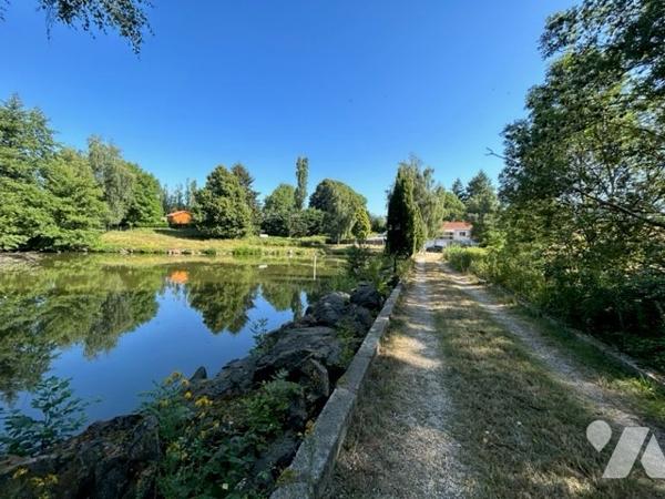 Maison dans la nature avec étang et piscine couverte.