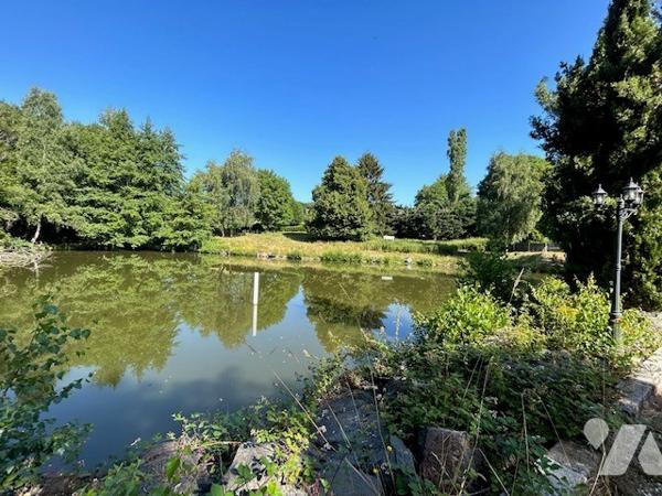 Maison dans la nature avec étang et piscine couverte.