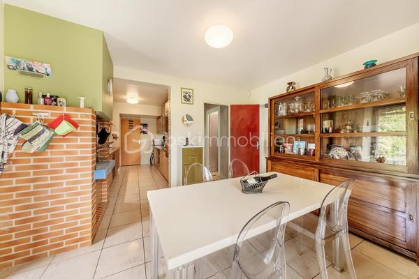 Une maison qui invite à ralentir…

Certaines propriétés séduisent par leurs prestations. 
D'autres procurent, dès les premiers instants, une sensation plus rare : celle de se sentir bien.

Ici, tout commence avant même d'ouvrir la porte.

Le jardin, entièrement aménagé au fil des années, ne cherche pas la perfection. 
Il est vivant, chaleureux, généreux. Les arbres ont grandi, les massifs se mêlent naturellement aux différents espaces de vie et chaque saison révèle une nouvelle palette de couleurs. C'est un jardin que l'on prend plaisir à parcourir, où l'on imagine les repas d'été, les après-midis au bord de la piscine ou tout simplement quelques instants de calme après une journée bien remplie.

Puis la maison se dévoile.

Ancienne longère entièrement rénovée, elle développe près de 230 m² habitables dans un équilibre réussi entre authenticité et confort contemporain. 
Difficile d'imaginer, en s'y installant, que les commerces, écoles et services sont accessibles en moins d'un kilomètre et que Rennes ne se trouve qu'à 15 minutes en voiture.

Le cœur de la maison est sans conteste sa magnifique pièce de vie sous plafond cathédrale. La lumière y entre généreusement grâce aux larges baies vitrées ouvertes sur le jardin, tandis que la charpente apparente rappelle avec élégance le caractère des lieux. (Pour vous aider à projeter votre futur intérieur, une proposition d'aménagement et de décoration virtuelle aux teintes naturelles est intégrée parmi les visuels.)

Pensée pour s'adapter à de nombreux projets de vie, la propriété s'organise autour de deux espaces communicants :

Le premier accueille une cuisine aménagée et équipée avec arrière-cuisine, un vaste salon-séjour, une chambre avec salle d'eau, une mezzanine aménagée en bureau ainsi qu'une suite parentale climatisée avec sa salle de bains.
Le second propose deux chambres, deux salles d'eau et un grand dortoir, offrant un confort idéal pour une grande famille, des adolescents en quête d'indépendance, l'accueil de proches ou encore un projet de chambres d'hôtes ou d’une profession libérale.

À l'extérieur, les 3 179 m² de terrain prolongent naturellement la maison. La piscine couverte s'intègre avec discrétion dans cet environnement verdoyant et permet d'en profiter bien au-delà de la belle saison.

Enfin, un élément mérite d'être souligné. Derrière le charme de cette demeure de caractère se cache une rénovation particulièrement aboutie. 
Son CLASSEMENT ÉNERGÉTIQUE B, rare pour une propriété des années 2000 et de cette superficie, témoigne d'un réel souci de conjuguer cachet, confort et performance énergétique. Pompe à chaleur, panneaux photovoltaïques et rénovation de qualité offrent aujourd'hui un confort de vie appréciable tout en répondant aux attentes de demain.

Cette maison ne se résume pas à ses volumes ou à ses prestations. 
C'est un lieu que l'on découvre, que l'on ressent… et dont il est difficile de repartir sans s'y projeter.