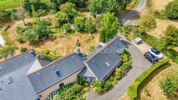 Une maison qui invite à ralentir…

Certaines propriétés séduisent par leurs prestations. 
D'autres procurent, dès les premiers instants, une sensation plus rare : celle de se sentir bien.

Ici, tout commence avant même d'ouvrir la porte.

Le jardin, entièrement aménagé au fil des années, ne cherche pas la perfection. 
Il est vivant, chaleureux, généreux. Les arbres ont grandi, les massifs se mêlent naturellement aux différents espaces de vie et chaque saison révèle une nouvelle palette de couleurs. C'est un jardin que l'on prend plaisir à parcourir, où l'on imagine les repas d'été, les après-midis au bord de la piscine ou tout simplement quelques instants de calme après une journée bien remplie.

Puis la maison se dévoile.

Ancienne longère entièrement rénovée, elle développe près de 230 m² habitables dans un équilibre réussi entre authenticité et confort contemporain. 
Difficile d'imaginer, en s'y installant, que les commerces, écoles et services sont accessibles en moins d'un kilomètre et que Rennes ne se trouve qu'à 15 minutes en voiture.

Le cœur de la maison est sans conteste sa magnifique pièce de vie sous plafond cathédrale. La lumière y entre généreusement grâce aux larges baies vitrées ouvertes sur le jardin, tandis que la charpente apparente rappelle avec élégance le caractère des lieux. (Pour vous aider à projeter votre futur intérieur, une proposition d'aménagement et de décoration virtuelle aux teintes naturelles est intégrée parmi les visuels.)

Pensée pour s'adapter à de nombreux projets de vie, la propriété s'organise autour de deux espaces communicants :

Le premier accueille une cuisine aménagée et équipée avec arrière-cuisine, un vaste salon-séjour, une chambre avec salle d'eau, une mezzanine aménagée en bureau ainsi qu'une suite parentale climatisée avec sa salle de bains.
Le second propose deux chambres, deux salles d'eau et un grand dortoir, offrant un confort idéal pour une grande famille, des adolescents en quête d'indépendance, l'accueil de proches ou encore un projet de chambres d'hôtes ou d’une profession libérale.

À l'extérieur, les 3 179 m² de terrain prolongent naturellement la maison. La piscine couverte s'intègre avec discrétion dans cet environnement verdoyant et permet d'en profiter bien au-delà de la belle saison.

Enfin, un élément mérite d'être souligné. Derrière le charme de cette demeure de caractère se cache une rénovation particulièrement aboutie. 
Son CLASSEMENT ÉNERGÉTIQUE B, rare pour une propriété des années 2000 et de cette superficie, témoigne d'un réel souci de conjuguer cachet, confort et performance énergétique. Pompe à chaleur, panneaux photovoltaïques et rénovation de qualité offrent aujourd'hui un confort de vie appréciable tout en répondant aux attentes de demain.

Cette maison ne se résume pas à ses volumes ou à ses prestations. 
C'est un lieu que l'on découvre, que l'on ressent… et dont il est difficile de repartir sans s'y projeter.