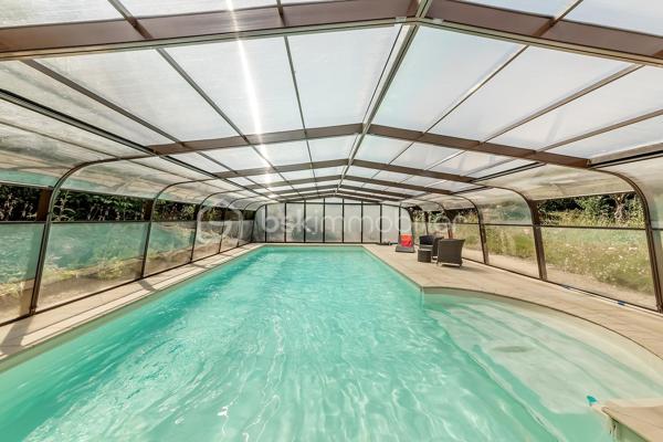 Une maison qui invite à ralentir…

Certaines propriétés séduisent par leurs prestations. 
D'autres procurent, dès les premiers instants, une sensation plus rare : celle de se sentir bien.

Ici, tout commence avant même d'ouvrir la porte.

Le jardin, entièrement aménagé au fil des années, ne cherche pas la perfection. 
Il est vivant, chaleureux, généreux. Les arbres ont grandi, les massifs se mêlent naturellement aux différents espaces de vie et chaque saison révèle une nouvelle palette de couleurs. C'est un jardin que l'on prend plaisir à parcourir, où l'on imagine les repas d'été, les après-midis au bord de la piscine ou tout simplement quelques instants de calme après une journée bien remplie.

Puis la maison se dévoile.

Ancienne longère entièrement rénovée, elle développe près de 230 m² habitables dans un équilibre réussi entre authenticité et confort contemporain. 
Difficile d'imaginer, en s'y installant, que les commerces, écoles et services sont accessibles en moins d'un kilomètre et que Rennes ne se trouve qu'à 15 minutes en voiture.

Le cœur de la maison est sans conteste sa magnifique pièce de vie sous plafond cathédrale. La lumière y entre généreusement grâce aux larges baies vitrées ouvertes sur le jardin, tandis que la charpente apparente rappelle avec élégance le caractère des lieux. (Pour vous aider à projeter votre futur intérieur, une proposition d'aménagement et de décoration virtuelle aux teintes naturelles est intégrée parmi les visuels.)

Pensée pour s'adapter à de nombreux projets de vie, la propriété s'organise autour de deux espaces communicants :

Le premier accueille une cuisine aménagée et équipée avec arrière-cuisine, un vaste salon-séjour, une chambre avec salle d'eau, une mezzanine aménagée en bureau ainsi qu'une suite parentale climatisée avec sa salle de bains.
Le second propose deux chambres, deux salles d'eau et un grand dortoir, offrant un confort idéal pour une grande famille, des adolescents en quête d'indépendance, l'accueil de proches ou encore un projet de chambres d'hôtes ou d’une profession libérale.

À l'extérieur, les 3 179 m² de terrain prolongent naturellement la maison. La piscine couverte s'intègre avec discrétion dans cet environnement verdoyant et permet d'en profiter bien au-delà de la belle saison.

Enfin, un élément mérite d'être souligné. Derrière le charme de cette demeure de caractère se cache une rénovation particulièrement aboutie. 
Son CLASSEMENT ÉNERGÉTIQUE B, rare pour une propriété des années 2000 et de cette superficie, témoigne d'un réel souci de conjuguer cachet, confort et performance énergétique. Pompe à chaleur, panneaux photovoltaïques et rénovation de qualité offrent aujourd'hui un confort de vie appréciable tout en répondant aux attentes de demain.

Cette maison ne se résume pas à ses volumes ou à ses prestations. 
C'est un lieu que l'on découvre, que l'on ressent… et dont il est difficile de repartir sans s'y projeter.
