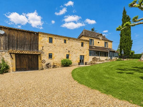 Belle maison de maître en pierre située dans un paysage vallonné en pleine campagne