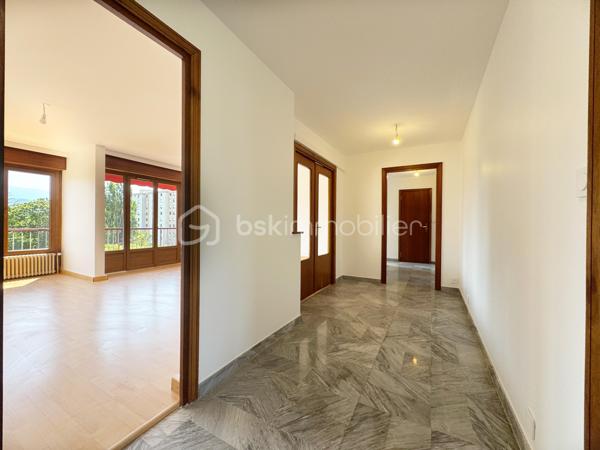 Au sein de la copropriété de standing Le Saint André à ÉCHIROLLES, cet appartement de 107,69 m² occupe le 4ᵉ étage sur 7. Traversant est / ouest, il offre une double orientation et des vues dégagées sur les massifs, du lever au coucher du soleil.

Une vaste entrée de 10,30 m² dessert un remarquable espace de vie de près de 36 m², organisé en double séjour avec sa salle à manger. Ouvert sur un balcon de 8,50 m², il domine le grand parc arboré de la copropriété, avec la chaîne de Belledonne en toile de fond : une vue dégagée et apaisante, sans aucun vis-à-vis. La cuisine, indépendante et de belles dimensions (près de 11 m²), se prolonge quant à elle par une loggia côté Vercors.

L'espace nuit se compose de trois chambres, toutes dotées d'une vue : deux ouvrent sur le massif du Vercors, la troisième sur le parc et la chaîne de Belledonne. La chambre principale est équipée son coin d'eau privatif et de son dressing. Une salle d'eau récente, un WC séparé, un second dressing et un dégagement de 7,60 m² entièrement équipé de placards complètent une distribution particulièrement fonctionnelle : les rangements ne manquent pas.

L'appartement a fait l'objet d'une rénovation complète : électricité entièrement refaite à neuf, peintures reprises dans l'ensemble des pièces, double vitrage récent de haute qualité, salle d'eau récente et climatisation dans la pièce de vie comme dans les chambres. Un logement prêt à vivre, sans aucun travaux à prévoir.

Une cave en sous-sol complète le bien. 
Deux places de parking sont par ailleurs proposées en sus, au prix de 7 000 € chacune.