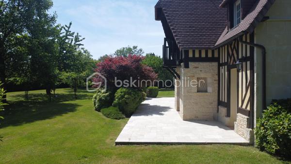 À seulement 25 minutes de Deauville et de Villers-sur-Mer, dans une commune calme et recherchée entre Pont-l’Évêque et Lisieux, découvrez cette maison normande familiale coup de cœur, idéale en résidence principale ou résidence secondaire en Normandie.

Dès l’entrée, une belle allée paysagée vous mène vers un environnement privilégié, verdoyant et sans vis-à-vis. Le terrain arboré et paysager offre de nombreux arbres fruitiers, un espace potager, ainsi qu’un potentiel d’aménagement pour piscine, rare sur le secteur.

Construite en 2002, cette maison récente de 146 m² au sol (130 m² habitables) allie confort moderne, qualité de construction et charme authentique normand. Une entrée avec porche dessert une spacieuse pièce de vie lumineuse de 40 m² avec cheminée insert, ouvrant sur une terrasse exposée plein sud avec vue dégagée sur le jardin.

La cuisine aménagée et équipée, au style chaleureux avec briques et pierres apparentes, renforce le caractère de cette maison de charme en Normandie. Le rez-de-chaussée comprend également un bureau, un WC indépendant avec lave-mains et un cellier.

À l’étage, l’espace nuit propose 4 chambres, dont une suite parentale avec salle d’eau privative et balcon, parfaite pour profiter du calme environnant. Une grande salle de bains avec baignoire, douche et double vasque, un WC séparé ainsi que de nombreux rangements complètent ce niveau.

En dépendances, vous bénéficierez de véritables atouts :

Un triple garage de 70 m² avec porte motorisée
Un studio indépendant de 20 m² avec coin cuisine, idéal pour location saisonnière, investissement locatif ou accueil familial
Un WC indépendant avec possibilité d’ajout d’une salle d’eau
Une cave à vin

La propriété dispose également d’un portail électrique, de nombreuses places de stationnement et d’un environnement calme, sans nuisance et sans vis-à-vis.