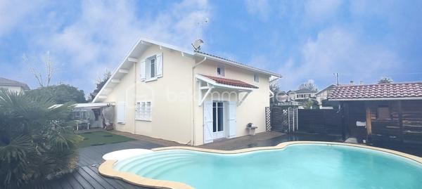 Située sur la commune de Saint-Paul-lès-Dax, aux portes immédiates de la ville de Dax, cette maison sur deux niveaux offre une surface habitable d’environ 130 m² et se trouve dans un environnement calme et privilégié, en bout d’impasse.
Dès l’entrée, le rez-de-chaussée propose un hall d'entrée, une cuisine indépendante, un salon/séjour lumineux avec cheminée de 35 m2, une grande buanderie/cellier très fonctionnelle de 17 m2, une chambre avec placard, une salle d’eau ainsi qu’un WC indépendant. L’étage accueille deux chambres supplémentaires, une seconde salle d’eau avec WC, un bureau et des combles aménagés offrant un espace complémentaire appréciable.
À l’extérieur, sur un terrain de 820 m2 entièrement clôt, le bien dispose d’un double garage attenant, d’une agréable terrasse couverte et d’une piscine avec traitement au sel, idéale pour profiter pleinement des beaux jours. Un chalet permet le rangement du matériel d’entretien, complété par un local piscine.
Cette maison bénéficie d’un cadre de vie paisible tout en restant proche des commerces, écoles, services et axes principaux menant à Dax.
Un bien complet et fonctionnel, parfait pour une famille à la recherche de confort et de tranquillité. Contactez-moi pour organiser une visite et découvrir tout son potentiel.