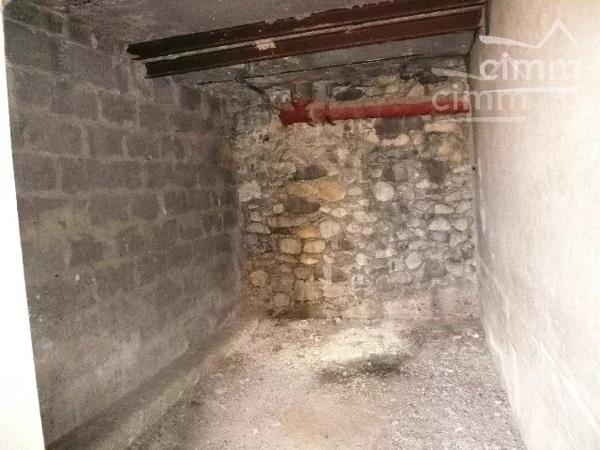 Garage pour motos avec porte en bois à deux vantaux, situé dans une cour.