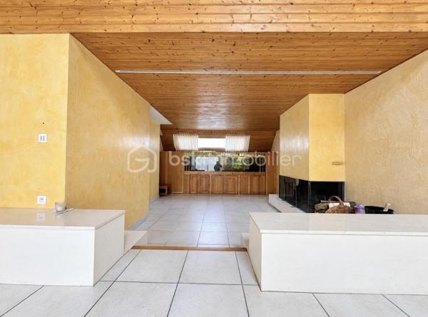 MAISON D’ARCHITECTE – 5 CHAMBRES – VIE DE PLAIN-PIED – TERRAIN 1 378 M² – GARAGE & CARPORT
Découvrez cette maison d’architecte familiale, lumineuse et sans vis-à-vis, implantée dans un environnement calme sur un magnifique terrain arboré et paysager de 1 378 m².
Elle offre de beaux volumes et une organisation idéale pour une famille, avec 4 chambres au rez-de-chaussée, dont une avec dressing et salle d’eau attenante.
La pièce de vie comprend une cuisine aménagée et équipée avec espace repas, ouverte sur un chaleureux salon-salle à manger avec cheminée. Les espaces de vie donnent directement sur deux terrasses, dont l’une dispose d’un espace repas extérieur abrité par un préau, avec vue sur le jardin.
Une salle de bains, deux WC, un débarras et de nombreux rangements complètent le rez-de-chaussée.
À l’étage : une 5e chambre, une mezzanine pouvant accueillir bureau, bibliothèque, salle de sport ou couchage supplémentaire, ainsi que des combles.
Garage, carport et cave complètent l’ensemble.
Les + : maison d’architecte, 5 chambres, vie de plain-pied, beaux volumes, luminosité, cheminée, deux terrasses, jardin paysager sans vis-à-vis, garage, carport, cave et transports scolaires desservant directement la rue.
Une maison familiale aux volumes généreux, où les espaces de vie s’ouvrent naturellement sur les terrasses et le jardin.