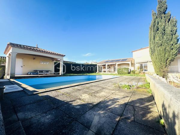 OUVEILLAN – Élégante villa avec piscine et art de vivre méditerranéen – 170 m² – Parcelle de 1 605 m² – 4 CHAMBRES (ou 3 plus BUREAU)

À quelques minutes de Narbonne et des plages, dans un environnement résidentiel calme et recherché, cette propriété dévoile un cadre de vie privilégié où confort et douceur de vivre se conjuguent parfaitement.

Dès les premiers regards, le charme opère : implantée sur une parcelle paysager de 1 605 m², exposée plein sud, la villa s’organise autour d’un espace extérieur remarquable, sublimée par une superbe piscine, véritable cœur de la propriété, idéale pour des moments de détente en toute intimité.

Développant environ 170 m² habitables, la maison offre de beaux volumes baignés de lumière. Le séjour de 55 m², avec cheminée, s’ouvre naturellement sur la terrasse et l’espace piscine, créant une parfaite continuité entre intérieur et extérieur.

La cuisine indépendante, entièrement équipée, s’accompagne d’une arrière-cuisine fonctionnelle. Le rez-de-chaussée accueille également une chambre, un bureau, un dressing ainsi qu’une salle d’eau avec douche à l’italienne et baignoire.

À l’étage, deux chambres supplémentaires, une salle d’eau et un WC indépendant viennent compléter l’ensemble, offrant un espace nuit confortable et bien agencé.

À l’extérieur, tout est pensé pour profiter pleinement du climat méditerranéen : terrasse carrelée avec barbecue, espace détente, sauna et jardin arboré sans vis-à-vis.

Prestations : climatisation réversible, cheminée, menuiseries aluminium double vitrage, volets roulants électriques, garage et stationnements privatifs, portail électrique.

Une propriété aux accents de villégiature, idéale pour une résidence principale ou secondaire, où chaque détail invite à profiter d’un art de vivre ensoleillé.