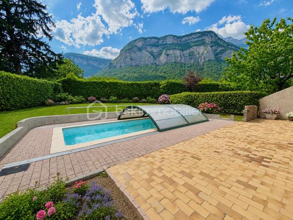 Dans un environnement calme et recherché, au sein d’une petite copropriété des années 80, découvrez cette agréable maison mitoyenne par le garage, implantée sur une parcelle de 591 m² et offrant une magnifique vue dégagée sur la Dent de Crolles.

D’une surface totale de 110 m² (106 m² loi Carrez), elle propose une distribution idéale pour une vie de famille. Le séjour, lumineux et chaleureux grâce à sa cheminée, s’ouvre directement sur la terrasse et l’espace piscine, invitant à profiter pleinement des beaux jours.

La cuisine équipée, aujourd’hui fonctionnelle mais à remettre au goût du jour, offre un beau potentiel d’aménagement. Le mur séparant la cuisine du séjour n’étant pas porteur, il est tout à fait envisageable de créer une grande pièce de vie ouverte et conviviale.

À l’étage, vous trouverez trois chambres confortables, toutes équipées de placards intégrés, dont deux particulièrement spacieuses. Une salle de bains avec baignoire ainsi qu’un second WC complètent ce niveau, tandis qu’un premier WC est situé au rez-de-chaussée pour plus de praticité.

Côté extérieur, le jardin offre un cadre paisible et une belle intimité. La piscine de 7 x 3 mètres, à rénover,  constitue un véritable atout pour créer un espace de détente à votre image.

Les prestations comprennent également des fenêtres en double vitrage avec volets roulants électriques, une cave, ainsi qu’un grand garage de 25 m² accessible directement depuis la maison. Deux places de stationnement privatives viennent compléter l’ensemble.

L’emplacement est un véritable point fort : commerces, écoles, mairie, marché dominical, équipements sportifs et activités pour les enfants sont accessibles à pied, offrant un quotidien pratique et agréable dans l’un des secteurs les plus appréciés de Crolles.

Une maison lumineuse, pleine de potentiel et idéalement située, qui n’attend plus que votre projet de vie.