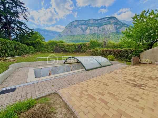 Dans un environnement calme et recherché, au sein d’une petite copropriété des années 80, découvrez cette agréable maison mitoyenne par le garage, implantée sur une parcelle de 591 m² et offrant une magnifique vue dégagée sur la Dent de Crolles.

D’une surface totale de 110 m² (106 m² loi Carrez), elle propose une distribution idéale pour une vie de famille. Le séjour, lumineux et chaleureux grâce à sa cheminée, s’ouvre directement sur la terrasse et l’espace piscine, invitant à profiter pleinement des beaux jours.

La cuisine équipée, aujourd’hui fonctionnelle mais à remettre au goût du jour, offre un beau potentiel d’aménagement. Le mur séparant la cuisine du séjour n’étant pas porteur, il est tout à fait envisageable de créer une grande pièce de vie ouverte et conviviale.

À l’étage, vous trouverez trois chambres confortables, toutes équipées de placards intégrés, dont deux particulièrement spacieuses. Une salle de bains avec baignoire ainsi qu’un second WC complètent ce niveau, tandis qu’un premier WC est situé au rez-de-chaussée pour plus de praticité.

Côté extérieur, le jardin offre un cadre paisible et une belle intimité. La piscine de 7 x 3 mètres, à rénover,  constitue un véritable atout pour créer un espace de détente à votre image.

Les prestations comprennent également des fenêtres en double vitrage avec volets roulants électriques, une cave, ainsi qu’un grand garage de 25 m² accessible directement depuis la maison. Deux places de stationnement privatives viennent compléter l’ensemble.

L’emplacement est un véritable point fort : commerces, écoles, mairie, marché dominical, équipements sportifs et activités pour les enfants sont accessibles à pied, offrant un quotidien pratique et agréable dans l’un des secteurs les plus appréciés de Crolles.

Une maison lumineuse, pleine de potentiel et idéalement située, qui n’attend plus que votre projet de vie.