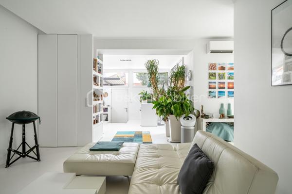 Dans une ancienne imprimerie réhabilitée en lofts contemporains, venez découvrir cet appartement de 93 m2 avec un extérieur de 18 m2, pensé pour les amateurs d’espaces atypiques.

Dès l’entrée, un espace bureau agrémenté de nombreux rangements sur mesure donne le ton et dessert une grande pièce de vie. Le séjour s’ouvre sur une cuisine américaine entièrement aménagée et équipée, formant un ensemble convivial et particulièrement agréable à vivre. La climatisation vient compléter le confort de cet espace.

Côté nuit, l’appartement dispose de deux chambres avec placards intégrés, ainsi que d’une salle de bains, d’une salle d’eau et de WC séparés. Une buanderie apporte également un espace de rangement et de service appréciable au quotidien.

L’un des véritables atouts du bien réside dans son extérieur privatif. Accessible directement depuis les pièces de vie grâce aux larges ouvertures, cette terrasse bénéficie d’un environnement particulièrement préservé et sans vis-à-vis. Un espace rare en ville, idéal pour profiter des beaux jours en toute tranquillité.

L’ensemble séduit par ses lignes épurées et son parti pris décoratif autour du blanc, qui accentue la sensation de volume et donne à l’appartement une identité très personnelle.

Cet appartement bénéficie d’une excellente desserte avec le RER B et la ligne 4 du métro accessibles à pied, permettant de rejoindre facilement Paris.

Ses atouts :
Un appartement en parfait état, prêt à vivre
Le confort de la climatisation en toute saison
Une terrasse privative de 18 m², véritable prolongement des espaces de vie
Une place de parking équipée d’une borne de recharge électrique
Une copropriété jeune, à l’ambiance conviviale et agréable