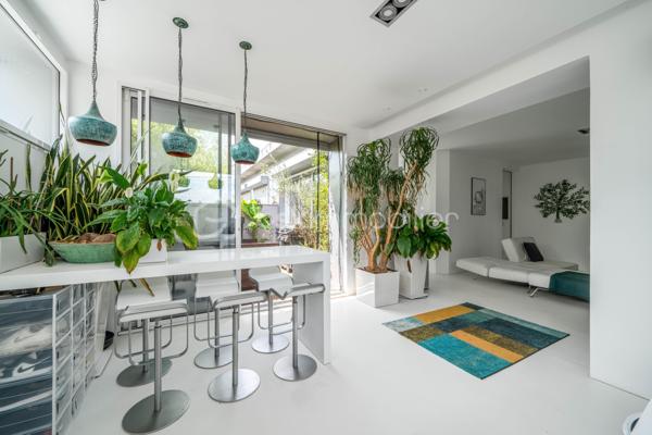 Dans une ancienne imprimerie réhabilitée en lofts contemporains, venez découvrir cet appartement de 93 m2 avec un extérieur de 18 m2, pensé pour les amateurs d’espaces atypiques.

Dès l’entrée, un espace bureau agrémenté de nombreux rangements sur mesure donne le ton et dessert une grande pièce de vie. Le séjour s’ouvre sur une cuisine américaine entièrement aménagée et équipée, formant un ensemble convivial et particulièrement agréable à vivre. La climatisation vient compléter le confort de cet espace.

Côté nuit, l’appartement dispose de deux chambres avec placards intégrés, ainsi que d’une salle de bains, d’une salle d’eau et de WC séparés. Une buanderie apporte également un espace de rangement et de service appréciable au quotidien.

L’un des véritables atouts du bien réside dans son extérieur privatif. Accessible directement depuis les pièces de vie grâce aux larges ouvertures, cette terrasse bénéficie d’un environnement particulièrement préservé et sans vis-à-vis. Un espace rare en ville, idéal pour profiter des beaux jours en toute tranquillité.

L’ensemble séduit par ses lignes épurées et son parti pris décoratif autour du blanc, qui accentue la sensation de volume et donne à l’appartement une identité très personnelle.

Cet appartement bénéficie d’une excellente desserte avec le RER B et la ligne 4 du métro accessibles à pied, permettant de rejoindre facilement Paris.

Ses atouts :
Un appartement en parfait état, prêt à vivre
Le confort de la climatisation en toute saison
Une terrasse privative de 18 m², véritable prolongement des espaces de vie
Une place de parking équipée d’une borne de recharge électrique
Une copropriété jeune, à l’ambiance conviviale et agréable