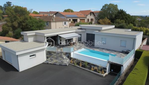 Une réalisation contemporaine confidentielle, pensée dans les moindres détails.
À Villerest, dans un environnement résidentiel particulièrement paisible, cette propriété contemporaine d’environ 185 m² habitables se distingue par son architecture, ses volumes et la qualité de ses prestations.
Achevée en 2023 et implantée sur un terrain d’environ 1 000 m², elle a été conçue autour d’une idée forte : privilégier les volumes, la lumière et la relation entre les espaces intérieurs et extérieurs.
Quelques marches suffisent à rejoindre le niveau principal de la maison, qui se développe ensuite entièrement de plain-pied. Une configuration particulièrement confortable et parfaitement adaptée à une vie familiale comme à une réception élégante.

La pièce maîtresse est sans conteste la pièce de vie de près de 90 m² avec sa cuisine entièrement équipée, espace repas et salon s’y articulent naturellement dans un volume spectaculaire, largement ouvert sur l’extérieur.
Les nombreuses baies vitrées et ouvertures offrent une luminosité exceptionnelle et permettent à la lumière naturelle d’accompagner les différents moments de la journée.
L’espace nuit se compose de trois chambres avec salles de bains privatives, tandis qu’une aile indépendante accueille une véritable suite parentale, composée d’une chambre, d’un grand dressing et d’une salle de bains raffinée avec douche, baignoire et WC.

À l’extérieur, la terrasse exposée sud-ouest prolonge naturellement les espaces de réception. Elle accueille une piscine à débordement et offre une agréable ouverture visuelle sur le lac de Villerest.

La propriété bénéficie également d’équipements à la hauteur de son architecture : grandes baies vitrées, BSO dans la pièce de vie, volets roulants dans les chambres, climatisation réversible, stores bannes, portail coulissant et garage double.

L’ensemble est complété par des extérieurs soigneusement aménagés, une vaste cour d’accueil et un espace végétalisé préservant l’intimité de la propriété.

Un bien rare sur le secteur, destiné à une clientèle à la recherche d’une architecture contemporaine affirmée, de volumes exceptionnels et d’un environnement privilégié.