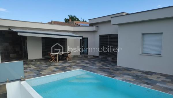 Une réalisation contemporaine confidentielle, pensée dans les moindres détails.
À Villerest, dans un environnement résidentiel particulièrement paisible, cette propriété contemporaine d’environ 185 m² habitables se distingue par son architecture, ses volumes et la qualité de ses prestations.
Achevée en 2023 et implantée sur un terrain d’environ 1 000 m², elle a été conçue autour d’une idée forte : privilégier les volumes, la lumière et la relation entre les espaces intérieurs et extérieurs.
Quelques marches suffisent à rejoindre le niveau principal de la maison, qui se développe ensuite entièrement de plain-pied. Une configuration particulièrement confortable et parfaitement adaptée à une vie familiale comme à une réception élégante.

La pièce maîtresse est sans conteste la pièce de vie de près de 90 m² avec sa cuisine entièrement équipée, espace repas et salon s’y articulent naturellement dans un volume spectaculaire, largement ouvert sur l’extérieur.
Les nombreuses baies vitrées et ouvertures offrent une luminosité exceptionnelle et permettent à la lumière naturelle d’accompagner les différents moments de la journée.
L’espace nuit se compose de trois chambres avec salles de bains privatives, tandis qu’une aile indépendante accueille une véritable suite parentale, composée d’une chambre, d’un grand dressing et d’une salle de bains raffinée avec douche, baignoire et WC.

À l’extérieur, la terrasse exposée sud-ouest prolonge naturellement les espaces de réception. Elle accueille une piscine à débordement et offre une agréable ouverture visuelle sur le lac de Villerest.

La propriété bénéficie également d’équipements à la hauteur de son architecture : grandes baies vitrées, BSO dans la pièce de vie, volets roulants dans les chambres, climatisation réversible, stores bannes, portail coulissant et garage double.

L’ensemble est complété par des extérieurs soigneusement aménagés, une vaste cour d’accueil et un espace végétalisé préservant l’intimité de la propriété.

Un bien rare sur le secteur, destiné à une clientèle à la recherche d’une architecture contemporaine affirmée, de volumes exceptionnels et d’un environnement privilégié.