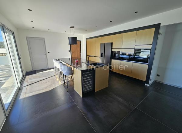 Une réalisation contemporaine confidentielle, pensée dans les moindres détails.
À Villerest, dans un environnement résidentiel particulièrement paisible, cette propriété contemporaine d’environ 185 m² habitables se distingue par son architecture, ses volumes et la qualité de ses prestations.
Achevée en 2023 et implantée sur un terrain d’environ 1 000 m², elle a été conçue autour d’une idée forte : privilégier les volumes, la lumière et la relation entre les espaces intérieurs et extérieurs.
Quelques marches suffisent à rejoindre le niveau principal de la maison, qui se développe ensuite entièrement de plain-pied. Une configuration particulièrement confortable et parfaitement adaptée à une vie familiale comme à une réception élégante.

La pièce maîtresse est sans conteste la pièce de vie de près de 90 m² avec sa cuisine entièrement équipée, espace repas et salon s’y articulent naturellement dans un volume spectaculaire, largement ouvert sur l’extérieur.
Les nombreuses baies vitrées et ouvertures offrent une luminosité exceptionnelle et permettent à la lumière naturelle d’accompagner les différents moments de la journée.
L’espace nuit se compose de trois chambres avec salles de bains privatives, tandis qu’une aile indépendante accueille une véritable suite parentale, composée d’une chambre, d’un grand dressing et d’une salle de bains raffinée avec douche, baignoire et WC.

À l’extérieur, la terrasse exposée sud-ouest prolonge naturellement les espaces de réception. Elle accueille une piscine à débordement et offre une agréable ouverture visuelle sur le lac de Villerest.

La propriété bénéficie également d’équipements à la hauteur de son architecture : grandes baies vitrées, BSO dans la pièce de vie, volets roulants dans les chambres, climatisation réversible, stores bannes, portail coulissant et garage double.

L’ensemble est complété par des extérieurs soigneusement aménagés, une vaste cour d’accueil et un espace végétalisé préservant l’intimité de la propriété.

Un bien rare sur le secteur, destiné à une clientèle à la recherche d’une architecture contemporaine affirmée, de volumes exceptionnels et d’un environnement privilégié.