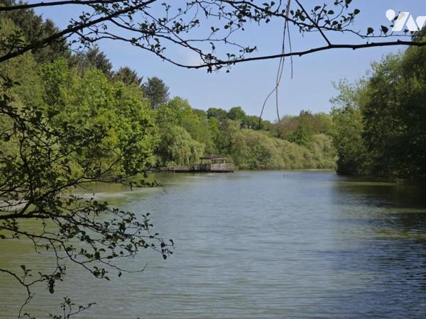 Terrain de loisirs avec plan d'eau d'environ un hectare, en partie arboré.