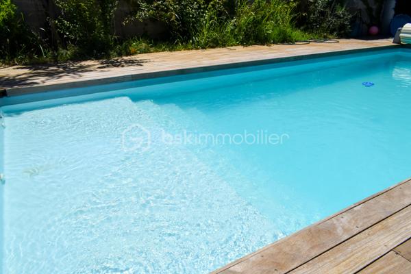 Découvrez cette charmante maison traditionnelle située dans un quartier pavillonnaire paisible de Saint-André-de-Sangonis.
Implantée sur une parcelle de 626 m², cette maison lumineuse de 103 m² environ offre un cadre de vie confortable et fonctionnel, idéal pour une famille à la recherche de tranquillité et d'espace.

Dès l'entrée, vous serez séduits par sa vaste pièce de vie de plus de 43 m², baignée de lumière. Cet espace convivial réunit salon, séjour et cuisine ouverte. La terrasse surélevée, accessible directement depuis la pièce de vie, constitue un véritable prolongement de la maison vers le jardin.

Dans le prolongement du séjour, quelques marches mènent à une pièce supplémentaire bénéficiant d'une baie vitrée et terrasse: Bureau, salon TV, salle de jeux ou quatrième chambre : cet espace s'adapte facilement à tous vos projets.

L'espace nuit se compose de trois chambres avec placard ainsi que d'une salle d'eau fonctionnelle, wc séparé.

Un garage isolé avec mezzanine et accès direct à la maison complète les prestations.

Côté confort, la maison dispose d'une climatisation gainable, de panneaux solaires,chauffe-eau thermodynamique ainsi que d'un adoucisseur d'eau. Eau du canal.

À l'extérieur, vous profiterez d'un agréable jardin arboré agrémenté de lauriers en fleurs, d'une piscine propice aux moments de détente et d'espaces à aménager selon vos envies. Deux portails facilitent l'accès à la propriété et permettent le stationnement de plusieurs véhicules, dont trois voitures sur la parcelle.

Les atouts :
• Maison 4 faces
• Pièce de vie de plus de 43 m²
• Possibilité de créer une 4ème chambre
• Climatisation gainable
• Panneaux solaires
• Piscine
• Garage isolé avec accès direct
• Stationnement multiple
• Terrain de 626 m²

Une maison lumineuse, évolutive et agréable à vivre, offrant un beau potentiel d'aménagement dans un environnement recherché.
Les visuels de home stanging facilitent la projection et permettent d'imaginer le potentiel d'aménagement de ce bien.