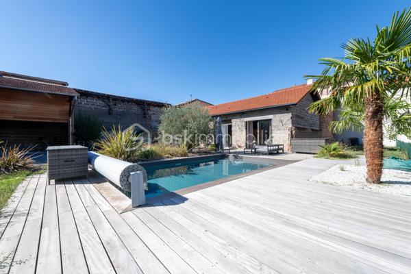 De l’espace pour recevoir, un patio pour s’isoler, une piscine pour profiter des beaux jours… À proximité immédiate du centre-ville de Roanne, cette maison de ville à l’esprit loft conjugue volumes remarquables et douceur de vivre, au calme, en retrait des axes passants.

Réhabilitée en 2021, elle développe environ une surface habitable de 224 m² habitables (surface carrez : 199 m²), sur un terrain clos et arboré de 746 m². Poutres apparentes, belles hauteurs sous plafond et larges ouvertures soulignent le caractère des lieux.

Au cœur de la maison, une pièce de vie d’environ 110 m² réunit cuisine équipée avec îlot central, espace repas et vaste salon. 

Ouverte sur le jardin et la piscine d’un côté, sur le patio intérieur de l’autre, elle invite à vivre autant dedans que dehors.

Le rez-de-chaussée accueille deux chambres donnant sur le patio, dont une suite parentale avec dressing et salle d’eau, ainsi qu’une buanderie et un WC indépendant.

À l’étage, une chambre, une salle de bains avec WC et une seconde pièce disposant d’un point d’eau et d’un WC permettent d’adapter les espaces à vos besoins : quatrième chambre, bureau ou salle de jeux.

À l’extérieur, terrasse, jardin et piscine au sel de 7 × 4 m composent un cadre idéal pour les repas d’été et les moments en famille. Un double carport avec espace de stockage à l’étage complète l’ensemble.

Classée A au DPE, la maison bénéficie d’une pompe à chaleur air/eau, d’un chauffage au sol, de menuiseries à double vitrage renforcé et d’un portail motorisé.

À proximité des écoles, des commerces et de la gare, une maison pour ceux qui souhaitent profiter de la ville tout en conservant de l’espace et un véritable extérieur.