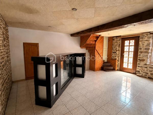 Située à proximité du centre, cette maison en pierre mitoyenne des 2 cotés offre un beau potentiel à ses futurs propriétaires. 
Nous commencerons la visite par la salle de 27m2 avec le charme des murs en pierres apparentes, en enfilade le salon de 20m2 puis toujours en enfilade la cuisine aménagée de 12m2. De la cuisine nous accédons à une cave de 13m2 et au wc séparé de 2m2. Pour un peu plus de rangement, de la cuisine nous accédons à une petite véranda non chauffée qui donne elle accès au jardin. 
Nous poursuivrons avec l'étage. Une mezzanine de 12m2 idéale pour y aménager un bureau ou encore un coin détente distribue l'accès aux trois chambres et à la salle de bain de 6m2 environ. La première chambre fait 14m2 dont un cabinet de toilettes privatif de 2m2 environ, la seconde chambre fait 18m2 et en enfilade vous avez une troisième chambre de 18m2 également. Possibilité de leur donner un accès privatif. 
Nous terminerons la visite par le grenier de 30m2 qui vous offre la possibilité de l'aménager. 
Coté extérieur, vous pourrez profiter de la parcelle de 185m2 entièrement close. Une pergola a été installée pour profiter de ses extérieurs tout en étant protégé. Pas de garage. 
Le mode de chauffage est électrique. La toiture est en ardoises naturelles. Les menuiseries bois sont en double vitrage sauf celle de la cuisine qu'il faudra envisager de changer si vous le souhaitez. La taxe foncière est de 870€. 
Toutes les commodités, écoles et commerces sont à proximité.  
Alors, cette annonce semble correspondre à vos critères de recherche ? Appelez-moi !
