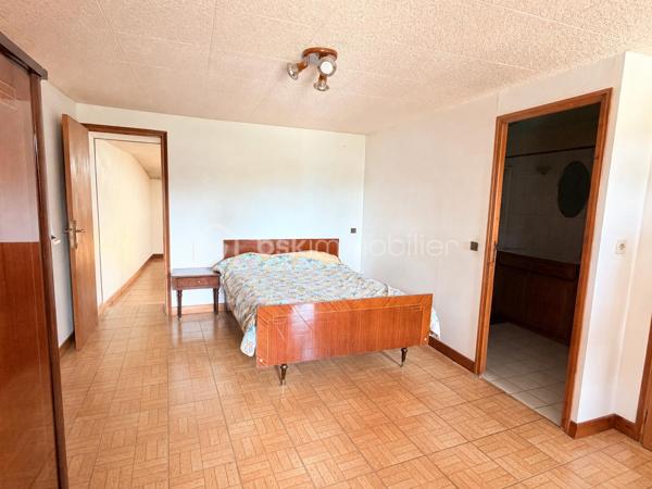 Située à proximité du centre, cette maison en pierre mitoyenne des 2 cotés offre un beau potentiel à ses futurs propriétaires. 
Nous commencerons la visite par la salle de 27m2 avec le charme des murs en pierres apparentes, en enfilade le salon de 20m2 puis toujours en enfilade la cuisine aménagée de 12m2. De la cuisine nous accédons à une cave de 13m2 et au wc séparé de 2m2. Pour un peu plus de rangement, de la cuisine nous accédons à une petite véranda non chauffée qui donne elle accès au jardin. 
Nous poursuivrons avec l'étage. Une mezzanine de 12m2 idéale pour y aménager un bureau ou encore un coin détente distribue l'accès aux trois chambres et à la salle de bain de 6m2 environ. La première chambre fait 14m2 dont un cabinet de toilettes privatif de 2m2 environ, la seconde chambre fait 18m2 et en enfilade vous avez une troisième chambre de 18m2 également. Possibilité de leur donner un accès privatif. 
Nous terminerons la visite par le grenier de 30m2 qui vous offre la possibilité de l'aménager. 
Coté extérieur, vous pourrez profiter de la parcelle de 185m2 entièrement close. Une pergola a été installée pour profiter de ses extérieurs tout en étant protégé. Pas de garage. 
Le mode de chauffage est électrique. La toiture est en ardoises naturelles. Les menuiseries bois sont en double vitrage sauf celle de la cuisine qu'il faudra envisager de changer si vous le souhaitez. La taxe foncière est de 870€. 
Toutes les commodités, écoles et commerces sont à proximité.  
Alors, cette annonce semble correspondre à vos critères de recherche ? Appelez-moi !