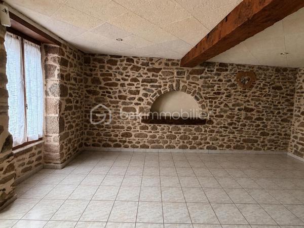 Située à proximité du centre, cette maison en pierre mitoyenne des 2 cotés offre un beau potentiel à ses futurs propriétaires. 
Nous commencerons la visite par la salle de 27m2 avec le charme des murs en pierres apparentes, en enfilade le salon de 20m2 puis toujours en enfilade la cuisine aménagée de 12m2. De la cuisine nous accédons à une cave de 13m2 et au wc séparé de 2m2. Pour un peu plus de rangement, de la cuisine nous accédons à une petite véranda non chauffée qui donne elle accès au jardin. 
Nous poursuivrons avec l'étage. Une mezzanine de 12m2 idéale pour y aménager un bureau ou encore un coin détente distribue l'accès aux trois chambres et à la salle de bain de 6m2 environ. La première chambre fait 14m2 dont un cabinet de toilettes privatif de 2m2 environ, la seconde chambre fait 18m2 et en enfilade vous avez une troisième chambre de 18m2 également. Possibilité de leur donner un accès privatif. 
Nous terminerons la visite par le grenier de 30m2 qui vous offre la possibilité de l'aménager. 
Coté extérieur, vous pourrez profiter de la parcelle de 185m2 entièrement close. Une pergola a été installée pour profiter de ses extérieurs tout en étant protégé. Pas de garage. 
Le mode de chauffage est électrique. La toiture est en ardoises naturelles. Les menuiseries bois sont en double vitrage sauf celle de la cuisine qu'il faudra envisager de changer si vous le souhaitez. La taxe foncière est de 870€. 
Toutes les commodités, écoles et commerces sont à proximité.  
Alors, cette annonce semble correspondre à vos critères de recherche ? Appelez-moi !