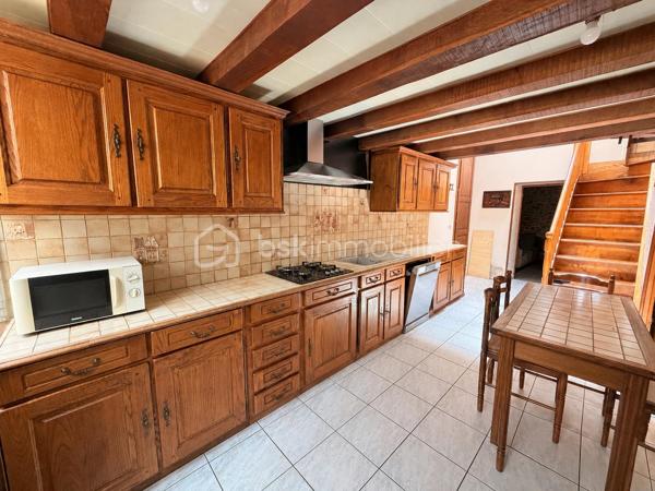 Située à proximité du centre, cette maison en pierre mitoyenne des 2 cotés offre un beau potentiel à ses futurs propriétaires. 
Nous commencerons la visite par la salle de 27m2 avec le charme des murs en pierres apparentes, en enfilade le salon de 20m2 puis toujours en enfilade la cuisine aménagée de 12m2. De la cuisine nous accédons à une cave de 13m2 et au wc séparé de 2m2. Pour un peu plus de rangement, de la cuisine nous accédons à une petite véranda non chauffée qui donne elle accès au jardin. 
Nous poursuivrons avec l'étage. Une mezzanine de 12m2 idéale pour y aménager un bureau ou encore un coin détente distribue l'accès aux trois chambres et à la salle de bain de 6m2 environ. La première chambre fait 14m2 dont un cabinet de toilettes privatif de 2m2 environ, la seconde chambre fait 18m2 et en enfilade vous avez une troisième chambre de 18m2 également. Possibilité de leur donner un accès privatif. 
Nous terminerons la visite par le grenier de 30m2 qui vous offre la possibilité de l'aménager. 
Coté extérieur, vous pourrez profiter de la parcelle de 185m2 entièrement close. Une pergola a été installée pour profiter de ses extérieurs tout en étant protégé. Pas de garage. 
Le mode de chauffage est électrique. La toiture est en ardoises naturelles. Les menuiseries bois sont en double vitrage sauf celle de la cuisine qu'il faudra envisager de changer si vous le souhaitez. La taxe foncière est de 870€. 
Toutes les commodités, écoles et commerces sont à proximité.  
Alors, cette annonce semble correspondre à vos critères de recherche ? Appelez-moi !