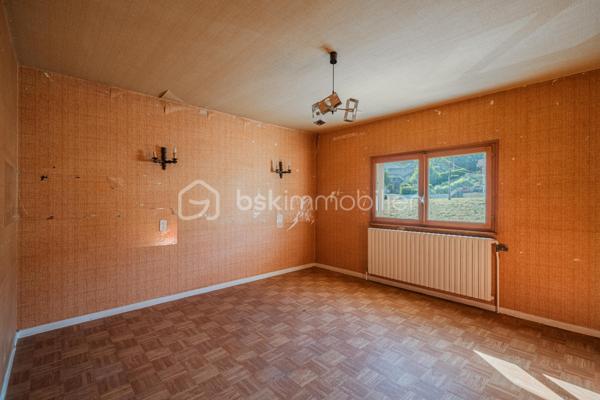 Sur les hauteurs de Rumilly Sud, dans un environnement paisible et verdoyant, cette maison de 131 m² offre un cadre de vie recherché avec une vue dégagée sur les montagnes et la campagne environnante.
Édifiée en 1970 sur un terrain d’environ 1 500 m² exposé Sud-Ouest, elle séduira autant une famille en quête d’espace qu’un artisan ou un amateur de rénovation à la recherche d’un bien à fort potentiel.
La maison bénéficie d’une organisation fonctionnelle et de volumes généreux permettant d’imaginer de nombreux projets d’aménagement.
Le niveau principal accueille une entrée, une cuisine indépendante aménagée, un salon-séjour séparé, trois chambres, une salle d’eau ainsi qu’un WC indépendant. Une vaste terrasse, faisant presque le tour de la maison, prolonge agréablement les espaces de vie et invite à profiter pleinement du panorama et du calme environnant.

À l’étage, deux chambres supplémentaires, une seconde salle d’eau et des greniers ouvrant la porte à différents usages : bureau, espace télétravail, salle de jeux ou pièces complémentaires selon les besoins.
Le sous-sol complet constitue un véritable atout avec un grand garage double, une buanderie avec douche et de larges espaces de rangement ou d’atelier particulièrement appréciables.
À l’extérieur, le terrain et le jardinet clôturé permettent de profiter d’un environnement agréable tout en conservant un entretien raisonnable, avec des stationnements disponibles devant la maison.
Des travaux de remise au goût du jour sont à prévoir, offrant l’opportunité de repenser les espaces et de révéler tout le potentiel de cette maison aux multiples possibilités.
Maison mitoyenne d’un côté, située dans une petite copropriété horizontale de deux lots seulement, sans charges et avec parties entièrement indépendantes.
Chauffage fioul complété par un poêle à bois.
Cette maison s’adresse aux acquéreurs capables de se projeter et recherchant avant tout un environnement calme, de beaux volumes et une vraie liberté de personnalisation.