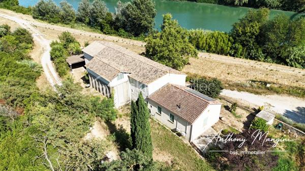 À découvrir sur le secteur de Saint-Gilles, ce magnifique mas en pierre datant de 1860 allie le charme de l'ancien à de généreux volumes. Édifié sur une parcelle de 2 157 m² exposée plein sud, il séduira les amateurs de biens authentiques en quête d'un lieu de vie plein de caractère.

La partie habitation, construite en 1948, développe environ 113 m² habitables. Elle comprend une cuisine indépendante, un salon chaleureux et lumineux avec ses pierres apparentes, deux chambres avec placards, une salle d'eau avec WC ainsi qu'une buanderie avec ancien lavoir. Le confort est assuré par un poêle à granulés et deux climatisations réversibles.

Dans le prolongement de l'habitation, une remise attenante d'environ 64 m², faisant office de garage et équipée d'une porte motorisée, dessert également une pièce ayant autrefois servi d'écurie.

L'ensemble se poursuit par un ancien chai ayant conservé ses six cuves à vin en béton d'origine. Au-dessus de la remise, un plateau d'environ 100 m², doté de nombreuses ouvertures, offre un vaste espace lumineux à aménager selon vos projets. Depuis celui-ci, un escalier mène à une remarquable pièce de 46 m², édifiée au-dessus du chai, baignée de lumière et sublimée par ses poutres apparentes. Un grand appentis complète harmonieusement la propriété.

À l'extérieur, vous profiterez d'un vaste espace de stationnement ainsi que d'un grand jardin clos, ensoleillé et agrémenté d'une terrasse.

Toiture refaite en 2017, menuiseries bois à double vitrage, exposition plein sud, DPE C viennent compléter les prestations de ce bien. La propriété est également équipée de panneaux solaires et bénéficie de l'eau du Rhône pour l'arrosage.

Un mas de caractère où authenticité, volumes et histoire se conjuguent pour offrir un cadre de vie unique. Les généreux volumes de cette propriété offrent de nombreuses possibilités d'aménagement, qu'il s'agisse d'agrandir l'habitation, de créer des espaces de réception, un atelier ou de développer un projet personnel ou professionnel.

Une visite s'impose pour en découvrir toute la richesse.

Les informations sur les risques auxquels ce bien est exposé sont disponibles sur le site Géorisques : www.georisques.gouv.fr