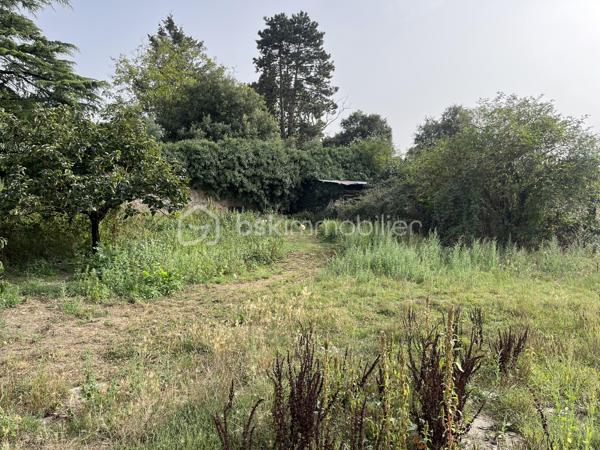 Dans le bourg de Nueil-les-Aubiers, terrain de 7 080 m², dont 600 m² constructibles, avec plan d'eau. Une partie de la parcelle est close par un mur en pierre.