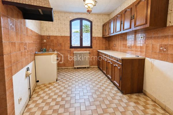 Construite en 1985 et toujours soigneusement entretenue, cette maison de plain-pied est implantée sur un terrain de 454 m².

L'entrée ouvre sur un couloir qui dessert, à droite, une grande pièce de vie d'environ 37 m² sur carrelage, lumineuse et ouverte sur la terrasse. À gauche se trouvent une salle à manger de plus de 15 m² et une cuisine aménagée. La maison comprend également une chambre d'environ 15 m² sur parquet, une salle de bain, un WC séparé et une buanderie-chaufferie.

Une pièce de stockage non chauffée et un accès au vide sanitaire, qui peut servir de rangement, complètent les volumes. L'ensemble offre environ 95m² de potentiel.

La maison bénéficie du double vitrage, de volets battants motorisés, d'une porte de garage sectionnelle motorisée et d'une isolation des combles refaite. Le chauffage est assuré par une chaudière fioul entretenue.

À l'extérieur, vous profiterez de terrasses, d'un jardin arboré et d'un garage sur dalle béton pouvant accueillir deux véhicules.

L'intérieur est à rafraîchir selon vos goûts. C'est une belle opportunité pour une première acquisition, un projet de plain-pied ou un investissement.