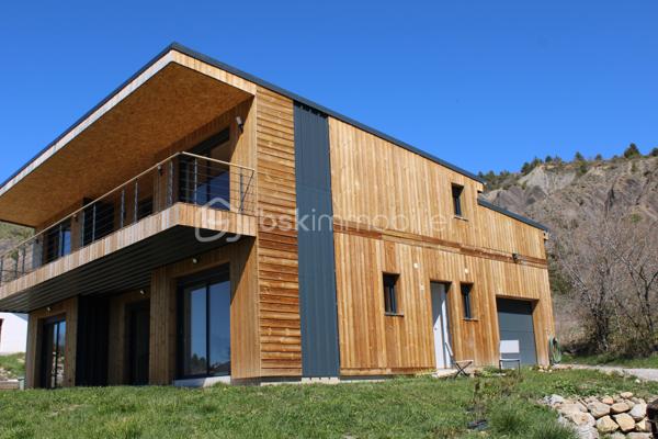 Calme absolu • Vue panoramique dégagée • Climat d'exception • Entre Ciel, Ski et Mer

Au cœur d’un environnement naturel préservé, dans un charmant village particulièrement ensoleillé de Haute-Provence, découvrez cette villa contemporaine en ossature bois de 140 m², pensée comme le refuge idéal pour vos week-ends et vacances. Alliant à la perfection lignes modernes, prestations haut de gamme et intégration paysagère, cette propriété offre un cadre de vie idyllique loin du tumulte urbain.
Une situation stratégique exclusive : à seulement 25 min de Sisteron (accès autoroute), 25 min de l’aérodrome de Tallard, 40 min de Gap, à 1h des stations de ski et à 1h30 de la Méditerranée.

Édifiée sur une parcelle de 802 m², la villa séduit par ses espaces fluides, sa clarté et la qualité de ses matériaux.

•	Le Rez-de-Chaussée (Vie de plain-pied) : L'entrée s’ouvre sur une superbe pièce à vivre de 45 m², véritable cœur de la maison. Elle accueille un salon-salle à manger baigné de lumière et une cuisine neuve de designer, entièrement équipée, ouverte sur le séjour. Ce niveau dispose également d'une suite parentale privative avec sa salle de bains haut de gamme et WC, ainsi que d'une buanderie fonctionnelle.
•	L’Étage (L'espace invités et détente) : Idéal pour recevoir vos proches, l’étage dessert 2 belles chambres spacieuses ainsi qu'un bureau (parfait pour le télétravail au vert). Le joyau architectural : Une magnifique terrasse coursive de 30 m² enveloppe l'étage et distribue l'ensemble des pièces, offrant à chacun un accès extérieur privé et un panorama spectaculaire sur la nature provençale dès le réveil.
•	Annexes & Éco-performance : Un garage de 20 m² avec porte sectionnelle automatisée complète la propriété. Côté confort, la villa est équipée d'un système de chauffage performant et éco-responsable (poêle à granules de dernière génération et chauffe-eau thermodynamique). Le plus : Un Permis de Construire (PC) est déjà accordé pour l'installation de panneaux solaires et d'un abri de jardin haut de gamme.

LA HAUTE-PROVENCE : LA NOUVELLE FRONTIÈRE DU LUXE AUTHENTIQUE

Plus qu'une maison, cette maison vous offre un art de vivre unique. La Haute Provence est devenue l'adresse confidentielle recherchée pour un tourisme nature, authentique et chic.
Depuis votre villa, accédez immédiatement aux plus beaux terrains de jeux outdoor : randonnées pédestres, circuits VTT, sites d'escalade et Via Ferrata, mondialement renommé de la Motte du Caire, ou encore vol à voile avec de nombreux aérodromes et parapente.

Notre avis : Un produit rare sur le marché. L'alliance parfaite entre le confort d'une villa neuve, un entretien facile idéal pour les séjours secondaires, et un emplacement d'exception garantissant une déconnexion totale à moins de deux heures de la Côte d'Azur.

1.	Zéro contrainte : Aucun travaux à prévoir, matériaux durables à faible entretien.
2.	Double saisonnalité rare : Skiez l'hiver à 1h, profitez des lacs et de la mer l'été, randonnez ou grimpez toute l'année sous le soleil légendaire de la Haute-Provence.
3.	Potentiel locatif haut de gamme : Forte demande pour le tourisme sportif et de reconnexion nature (marche, escalade, aéronautique à Tallard).
